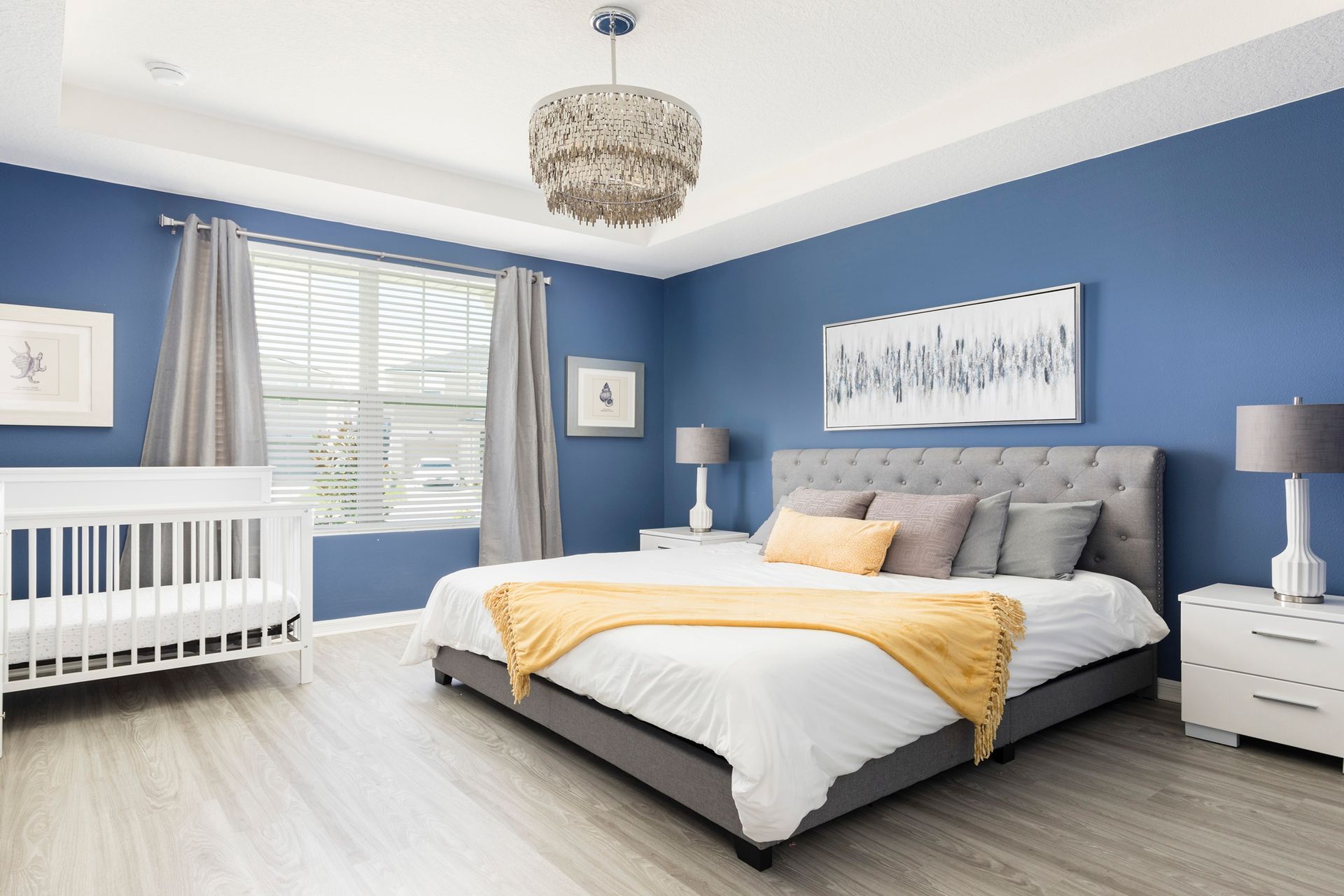 Elegant bedroom with cozy crib, navy accents, and chic chandelier!