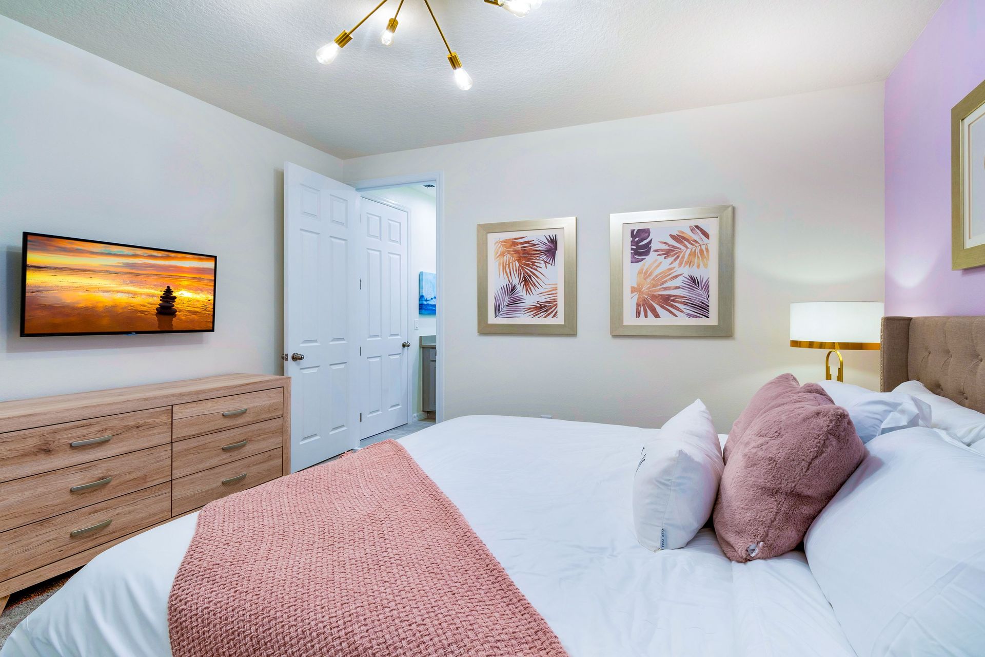 Stylish bedroom with soft pastel accents, cozy bedding, and TV!