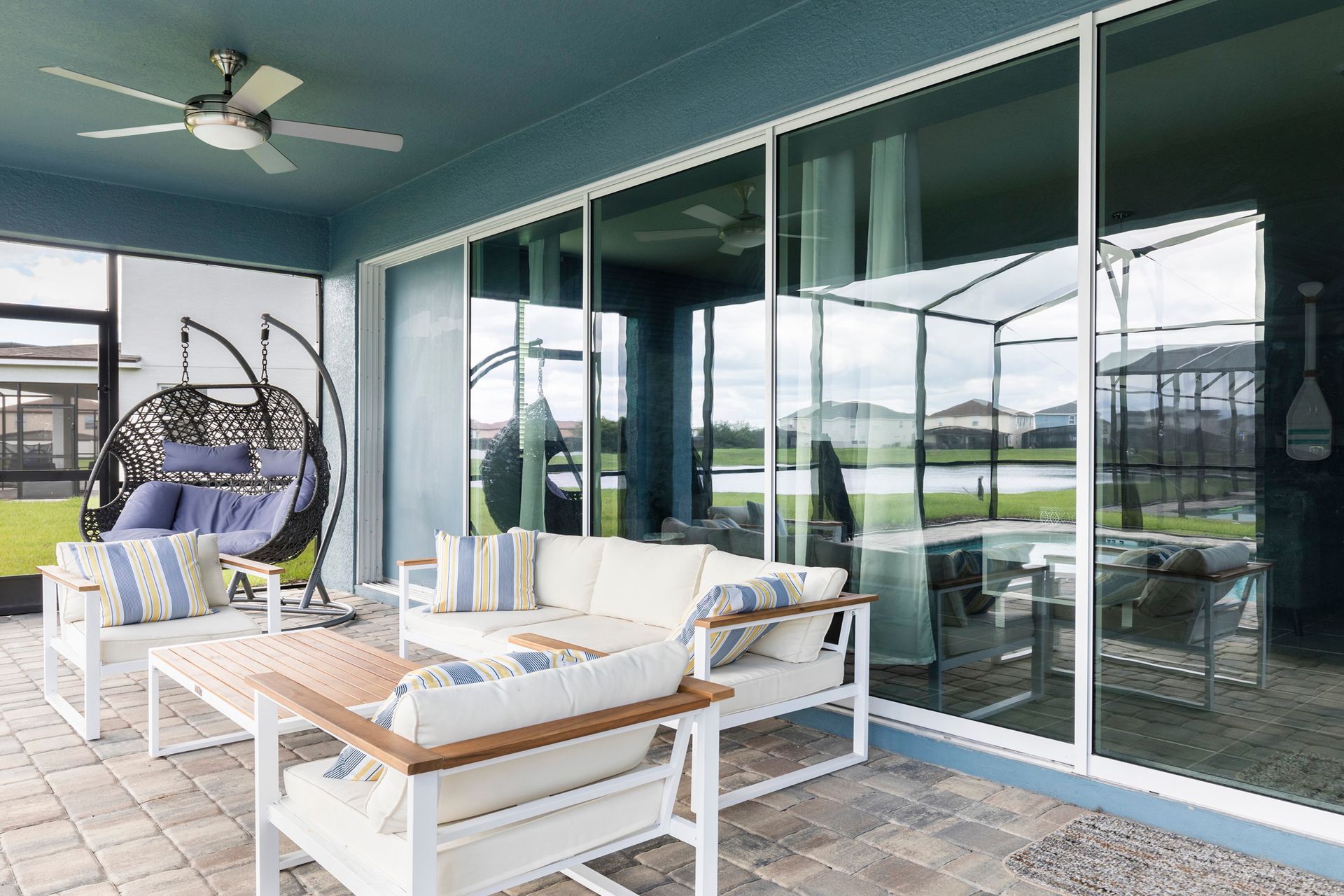 Relaxing screened patio with cozy seating, swing chair, and serene views!