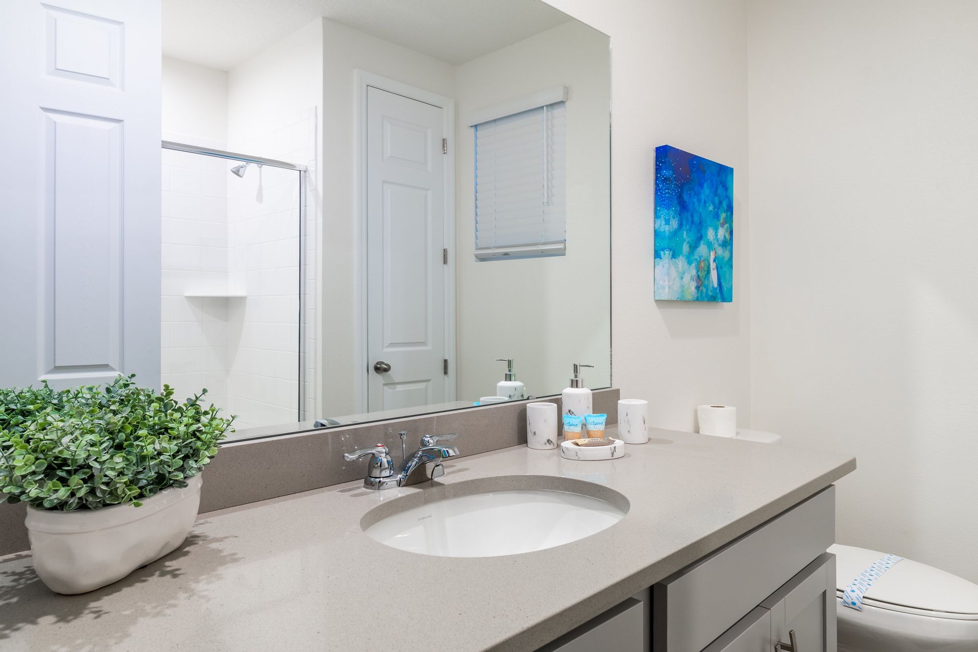Minimalist bathroom with gray vanity and vibrant blue art.