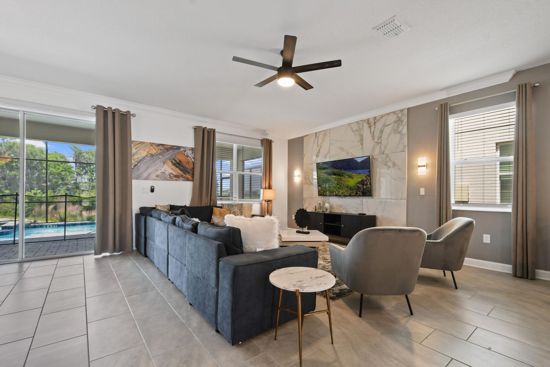 Enjoy quality time in this elegant living room with sleek decor, plush sofas, and a large TV, all surrounded by natural light and scenic views.