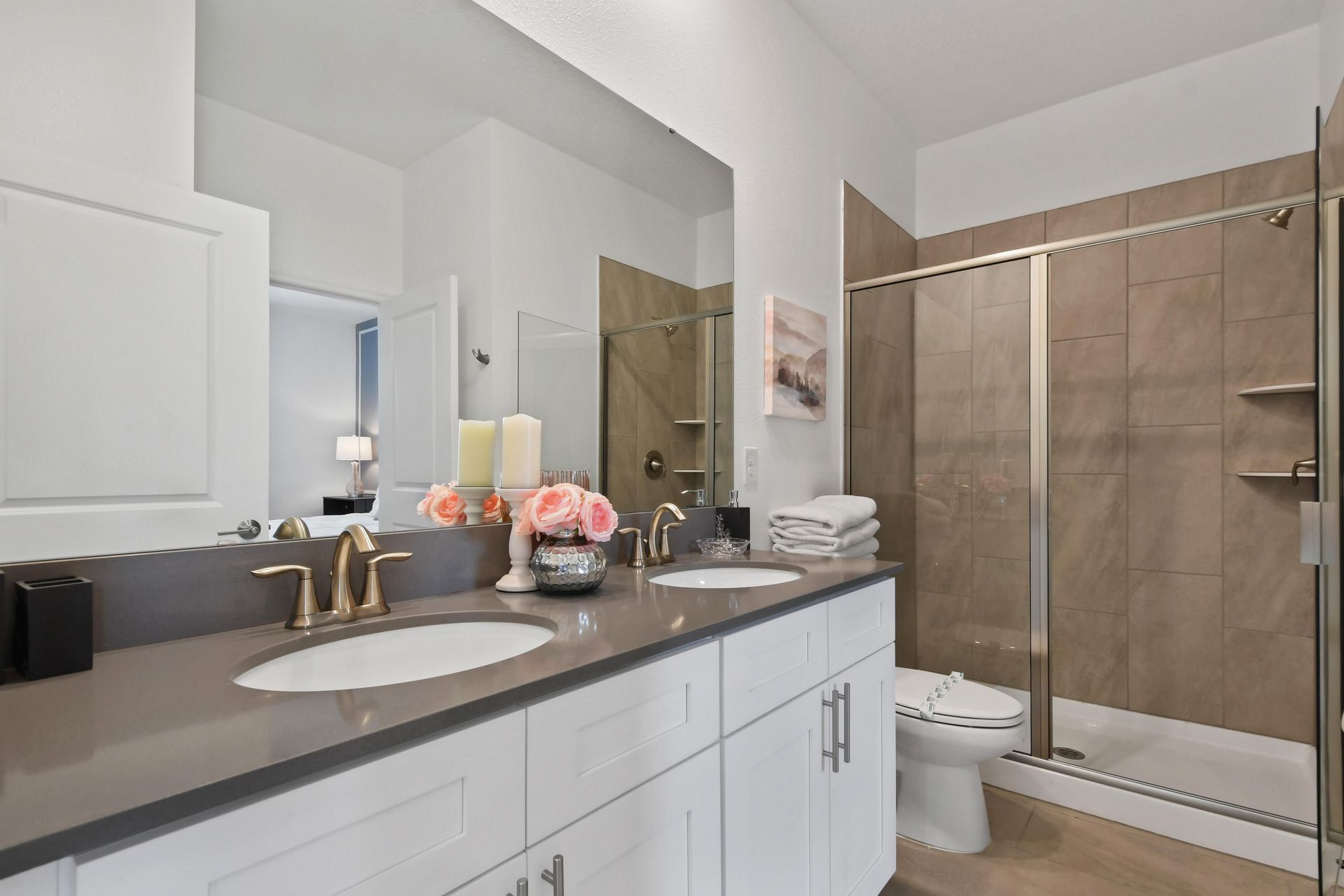 Elegant bathroom with a dual-sink vanity, glass-enclosed shower, and modern decor.