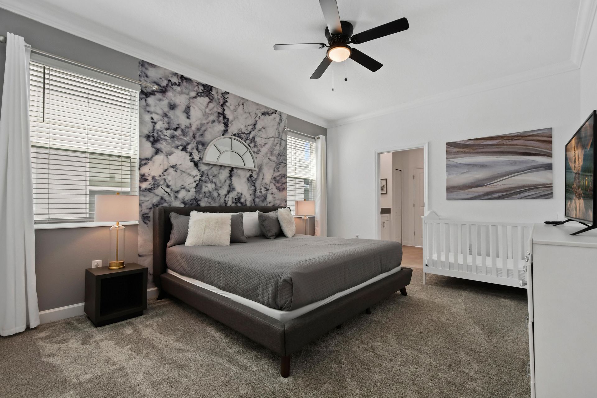 Spacious master suite with a king bed, elegant decor, and a cozy crib for comfort.