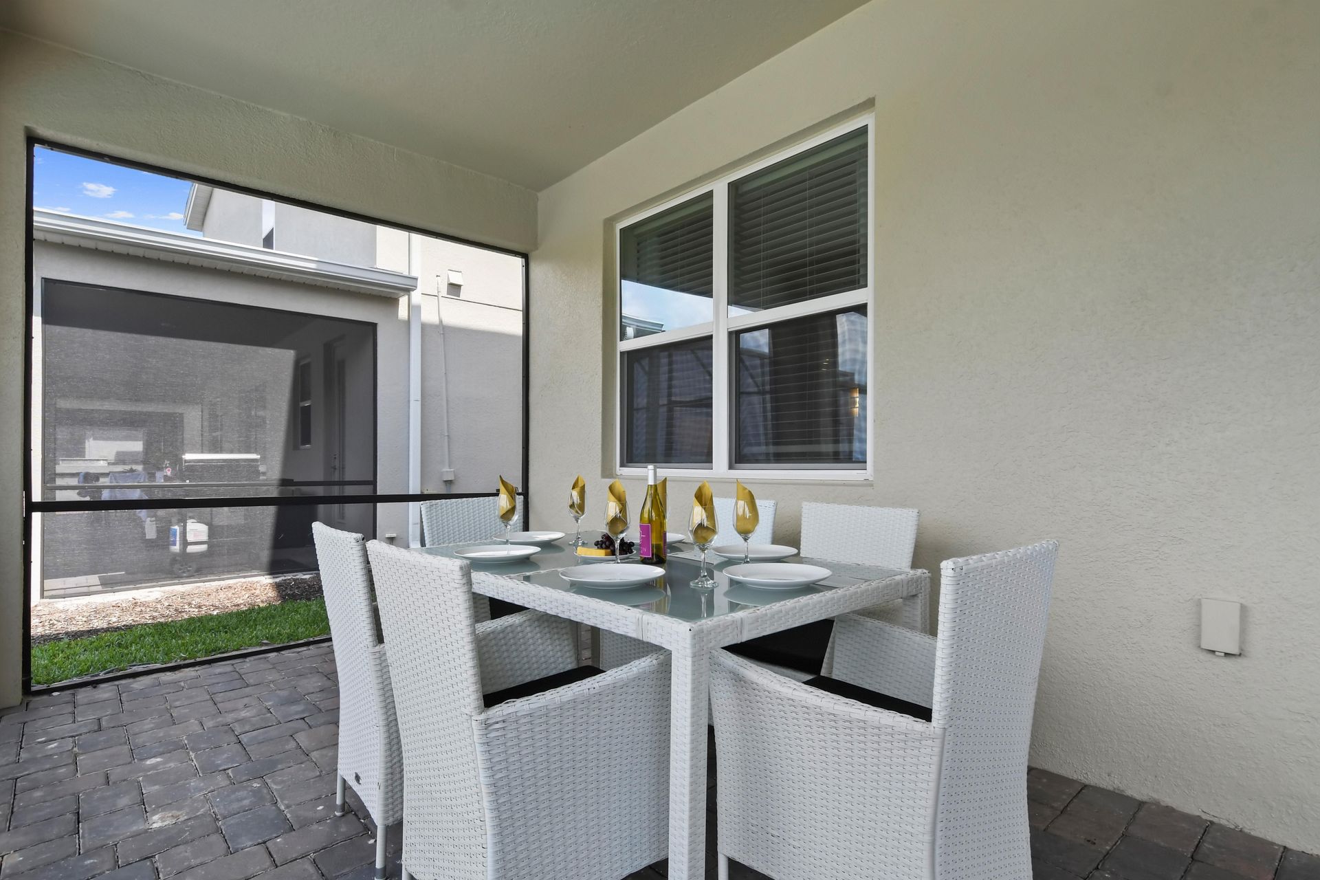 Elegant screened-in outdoor dining area with modern white seating for a relaxing meal.