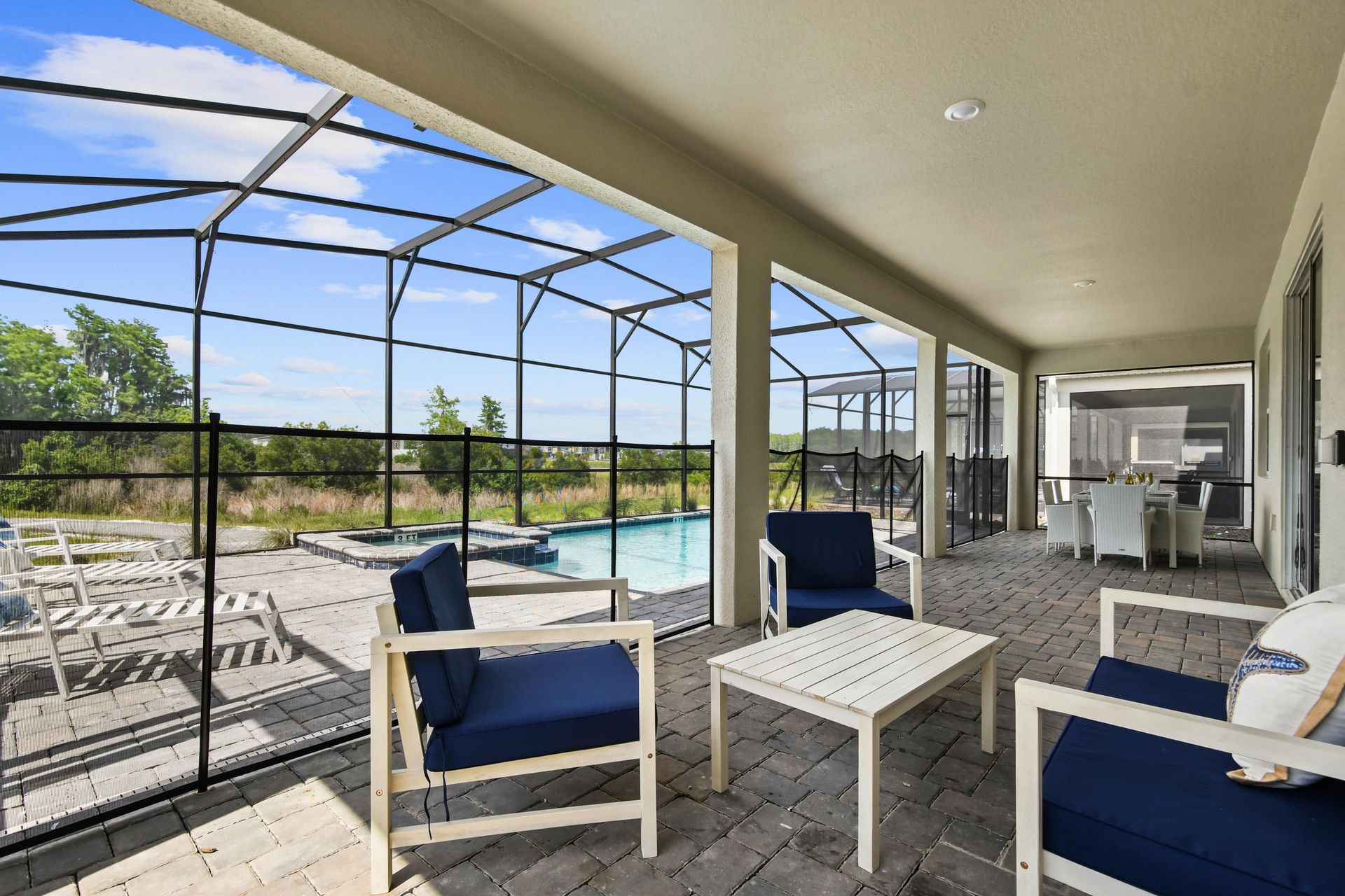 Spacious screened-in patio with pool views, cozy seating, and outdoor dining space.