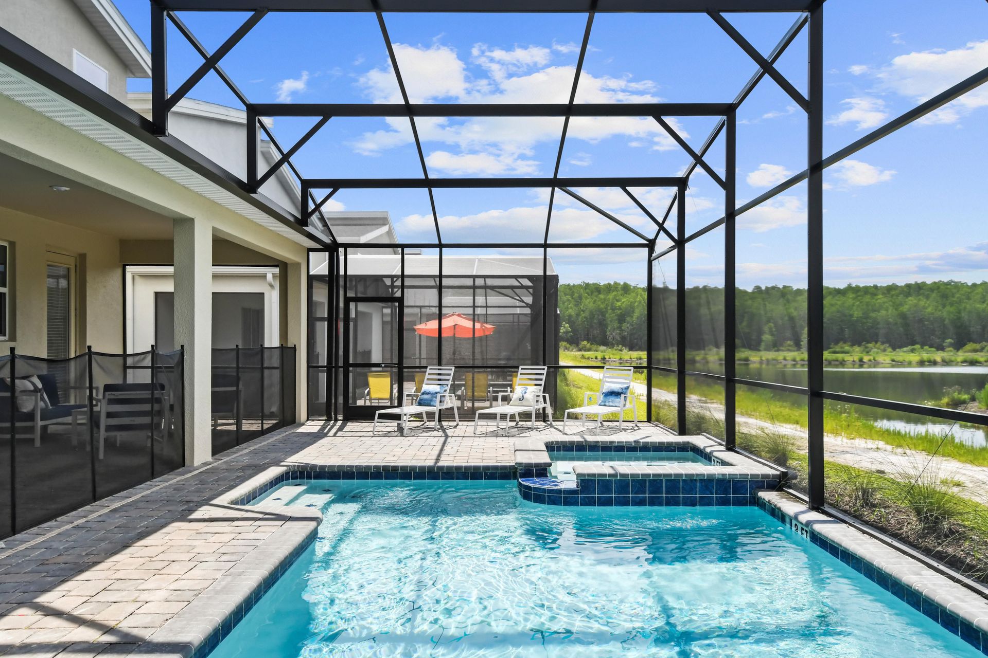 Screened-in pool and spa with lake views, lounge chairs, and a relaxing outdoor vibe.