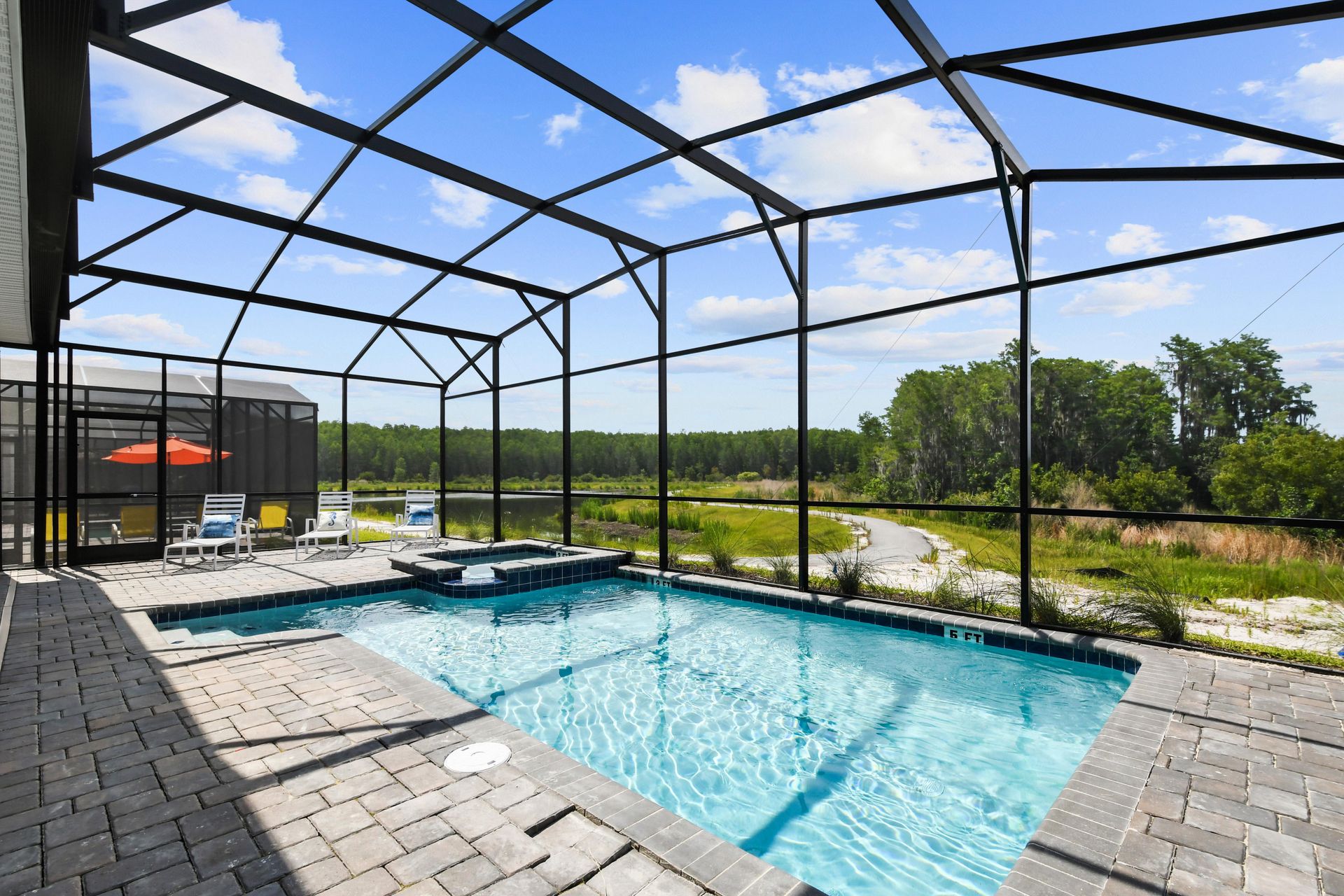 Screened-in pool and spa with lake views, lounge chairs, and a relaxing outdoor vibe.