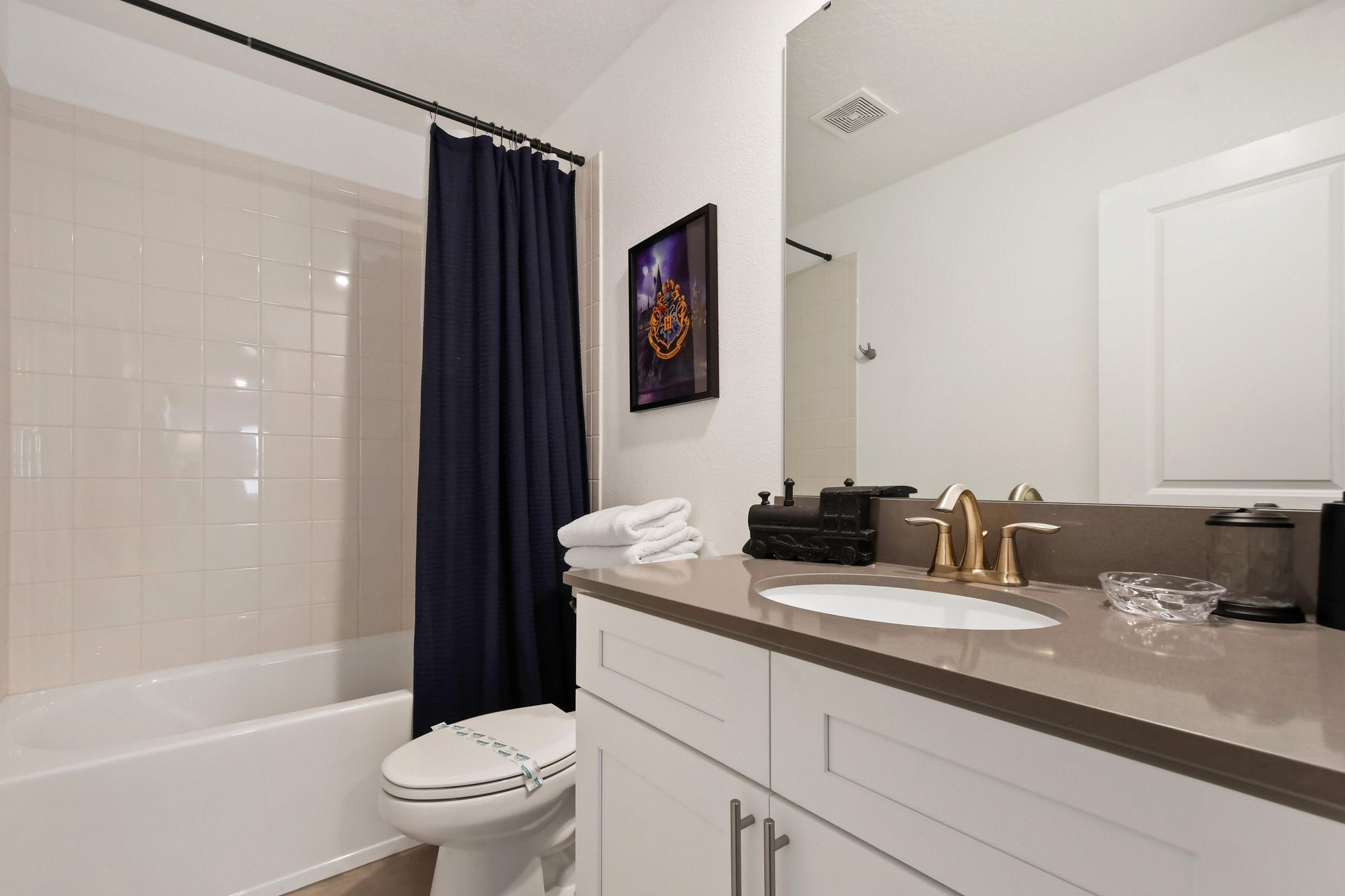 Stylish bathroom with a sleek vanity, gold accents, and a classic tub-shower combo.