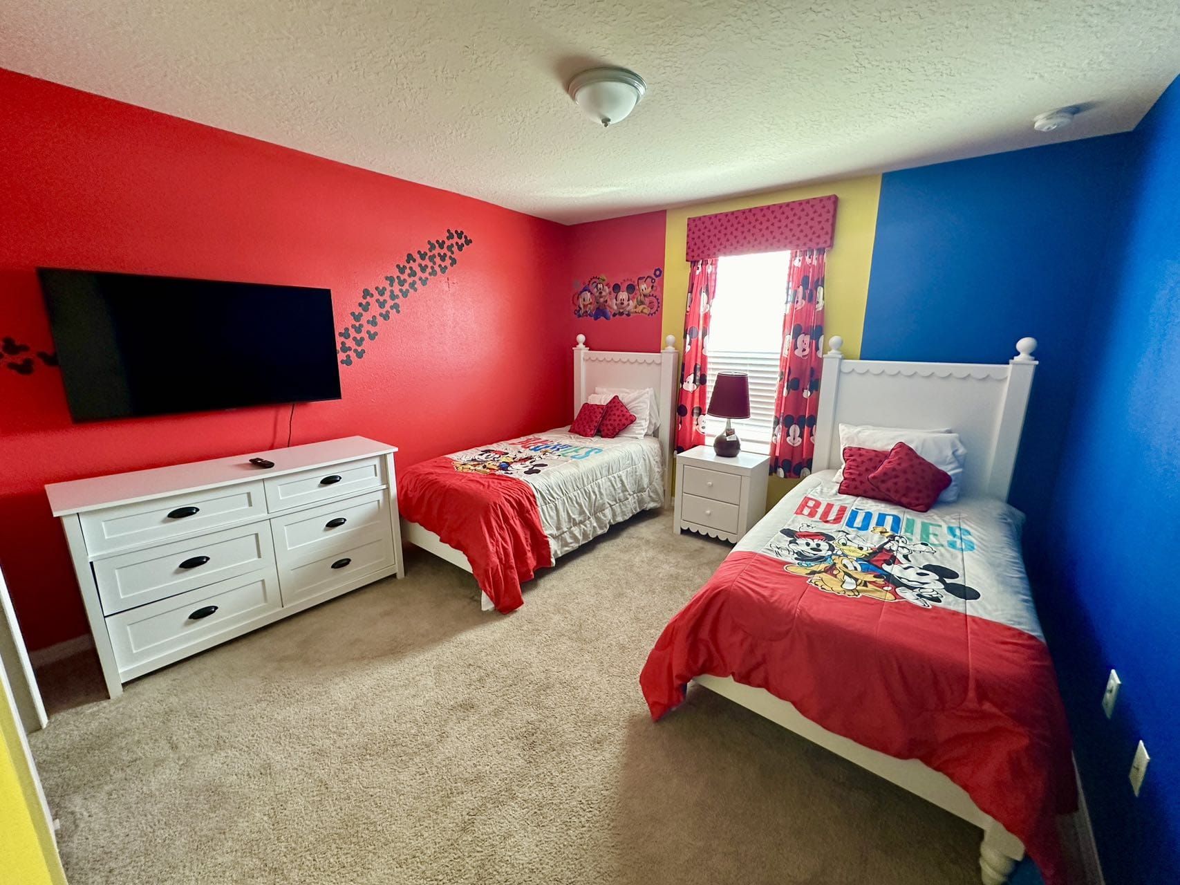 Colorful Disney-themed twin room with TV, perfect for kids and family fun.
