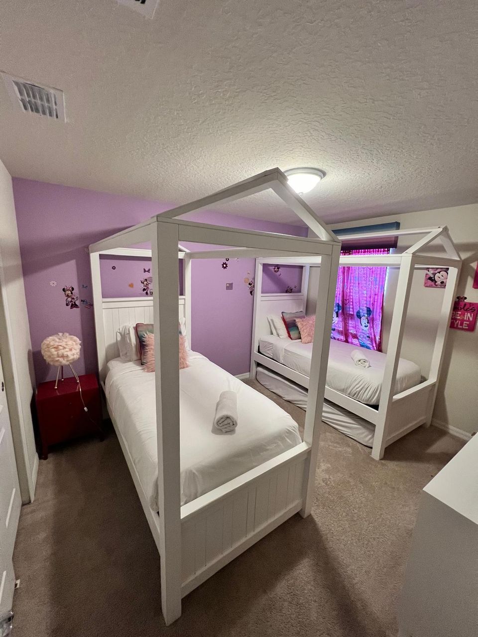 Charming kids' room with twin canopy beds, Disney decor, and cozy comfort.
