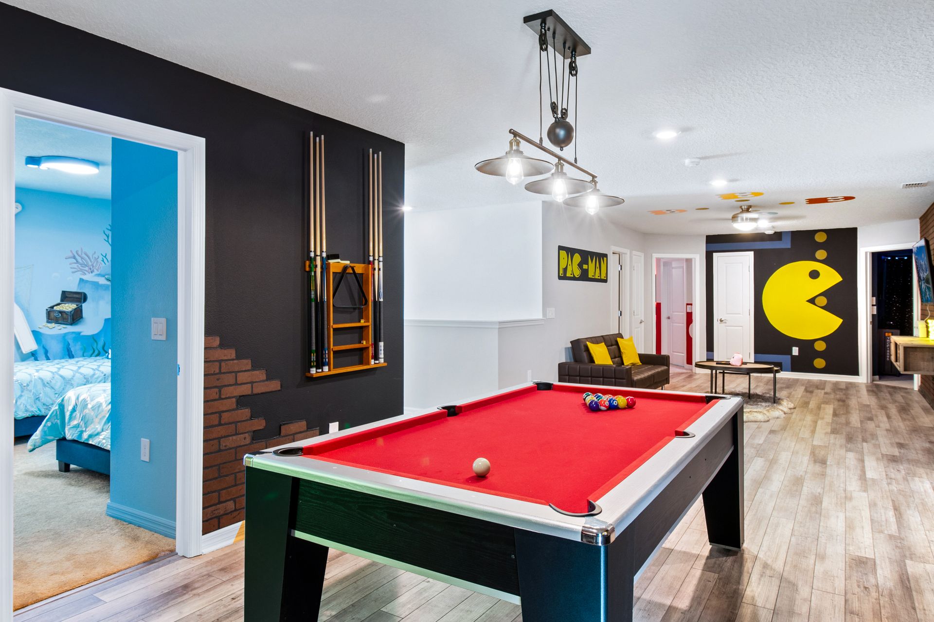 Fun-packed game room with a red pool table, arcade vibes & retro Pac-Man décor!