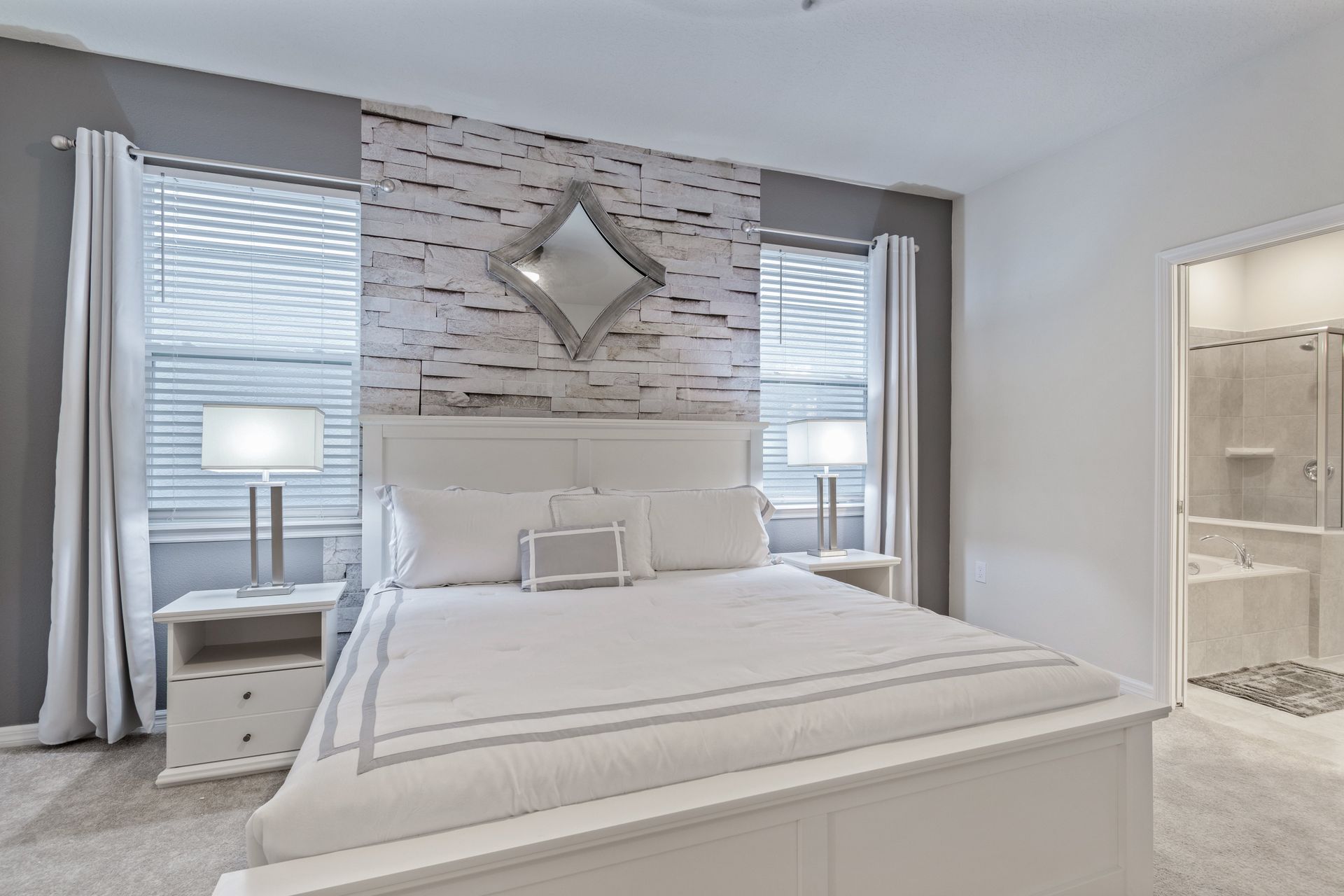 Elegant bedroom with a king bed, textured accent wall, and soft lighting.