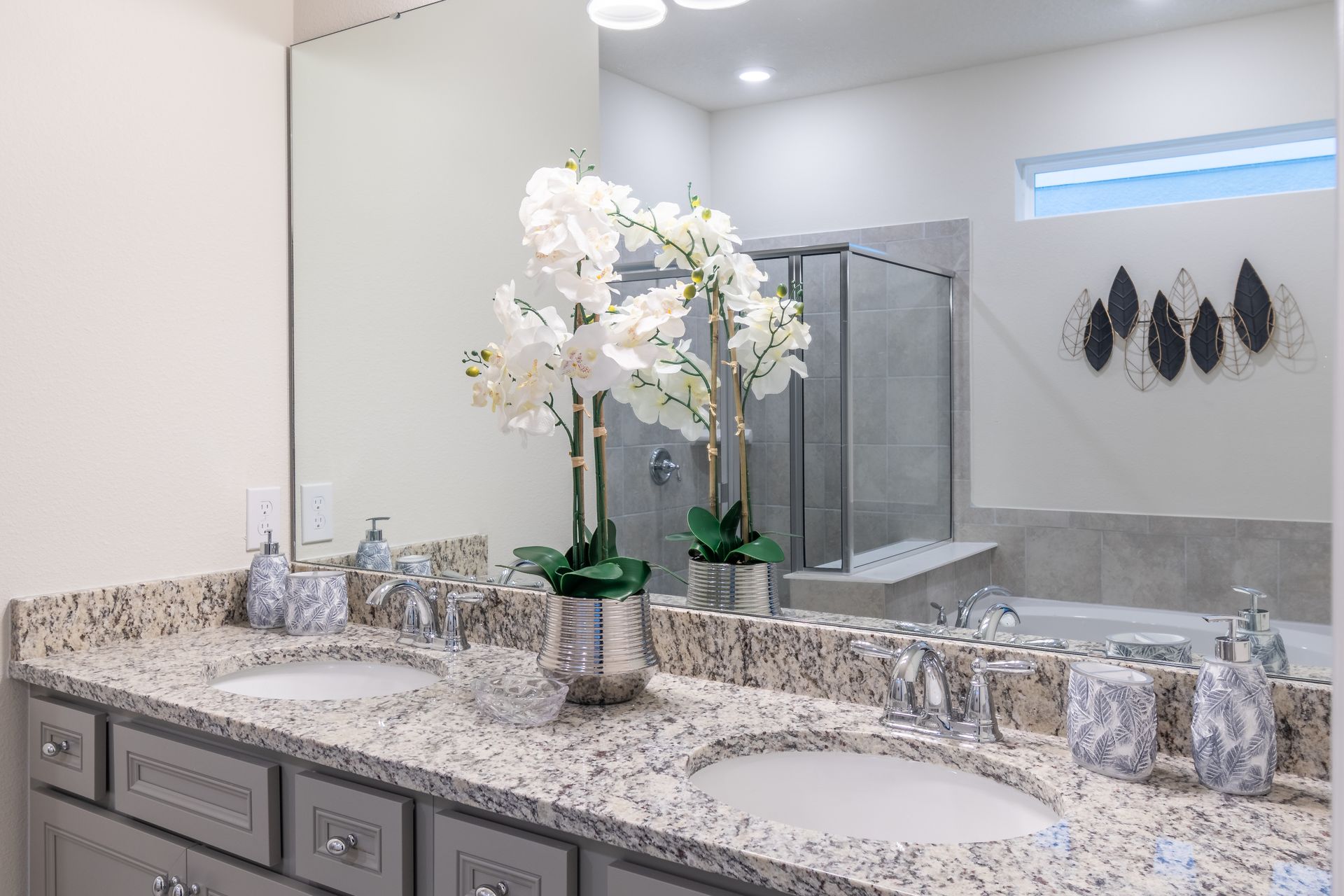 Elegant bathroom with double sinks, granite countertops, and a glass shower.