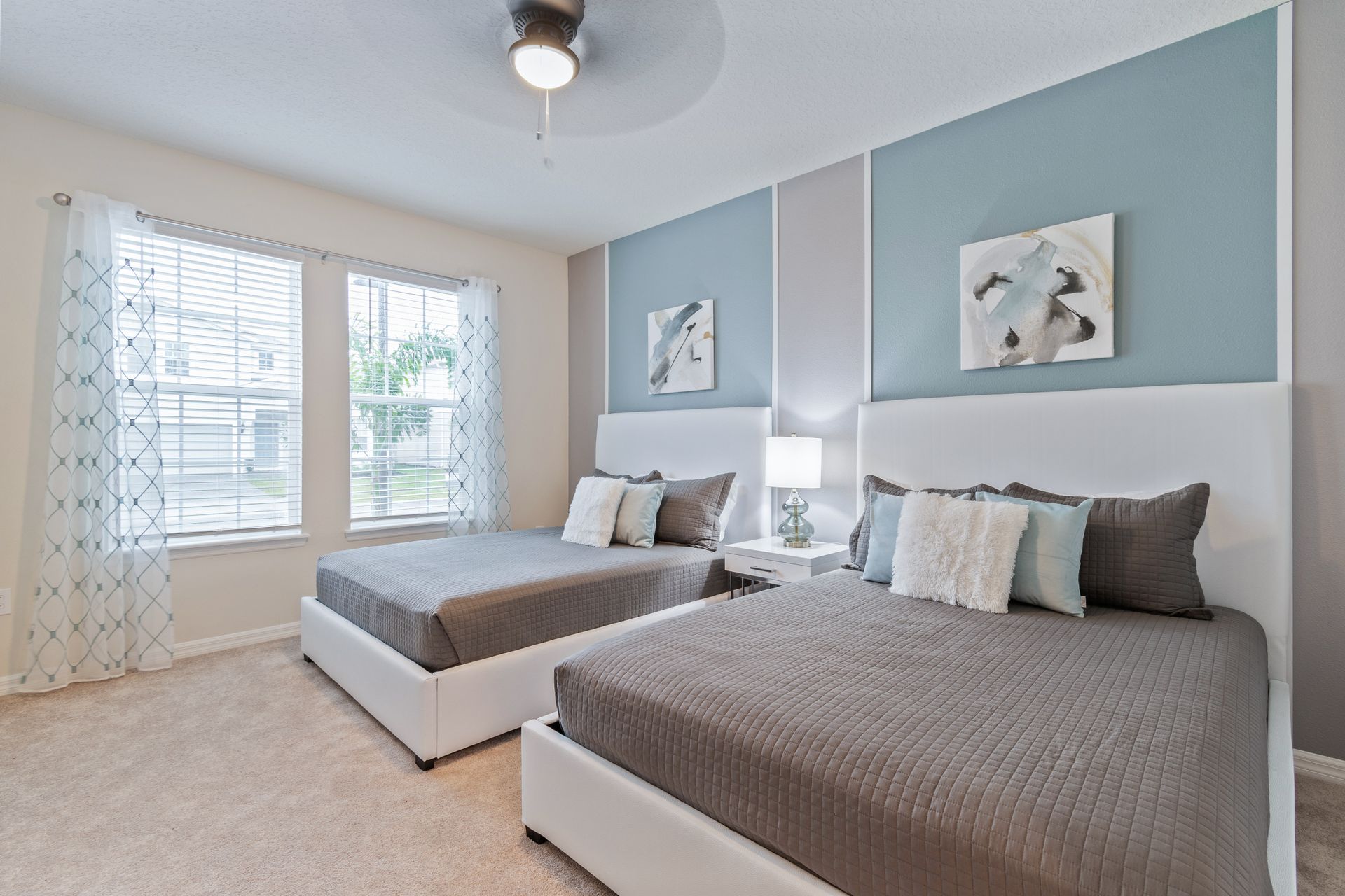 Bright and airy bedroom with two queen beds, stylish decor, and natural light.