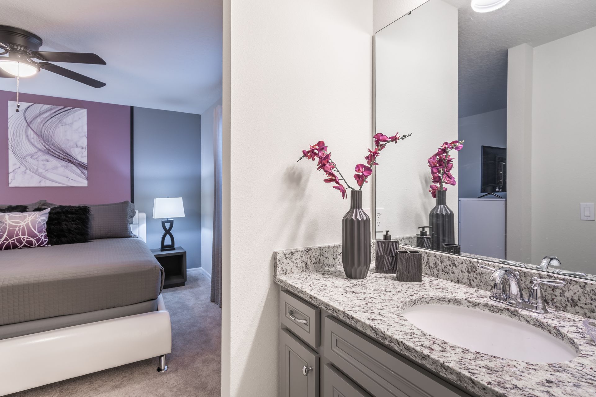 Modern bathroom with granite countertop, elegant decor, and bedroom access.