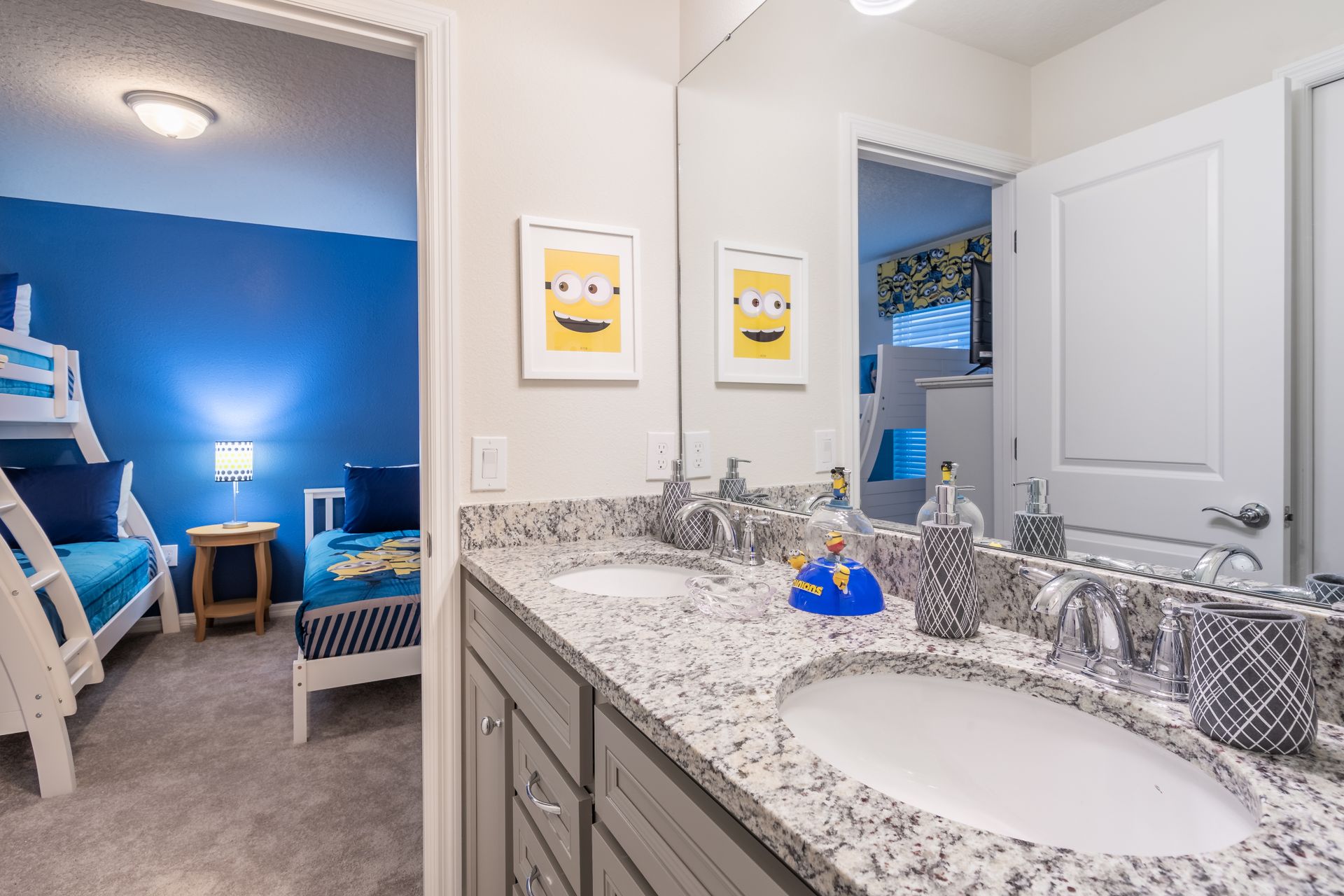 Bright bathroom with double sinks, granite counters, and a playful kids' theme.