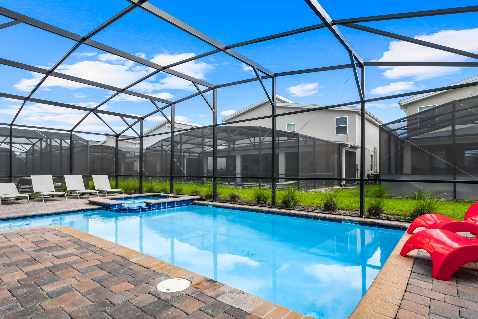 Spacious screened pool area with spa, lounge chairs, and vibrant seating for fun!