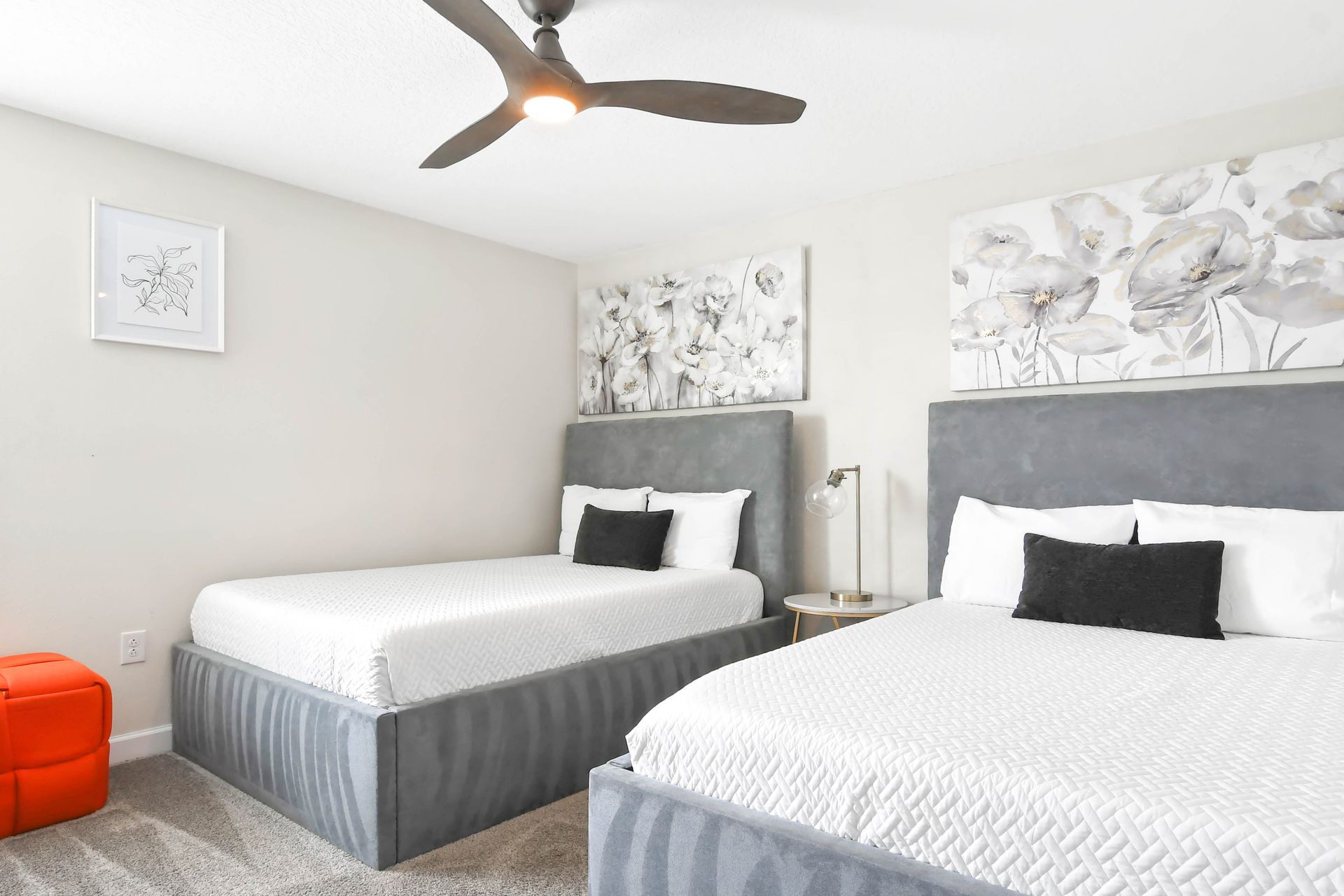 Chic twin bedroom with modern decor, cozy beds, floral accents, and natural light!