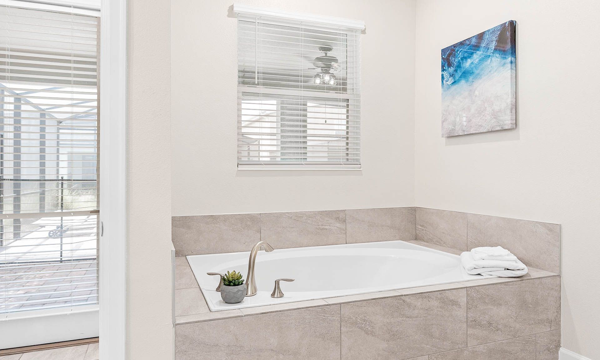 Relax in a spacious soaking tub with natural light and serene, modern decor!