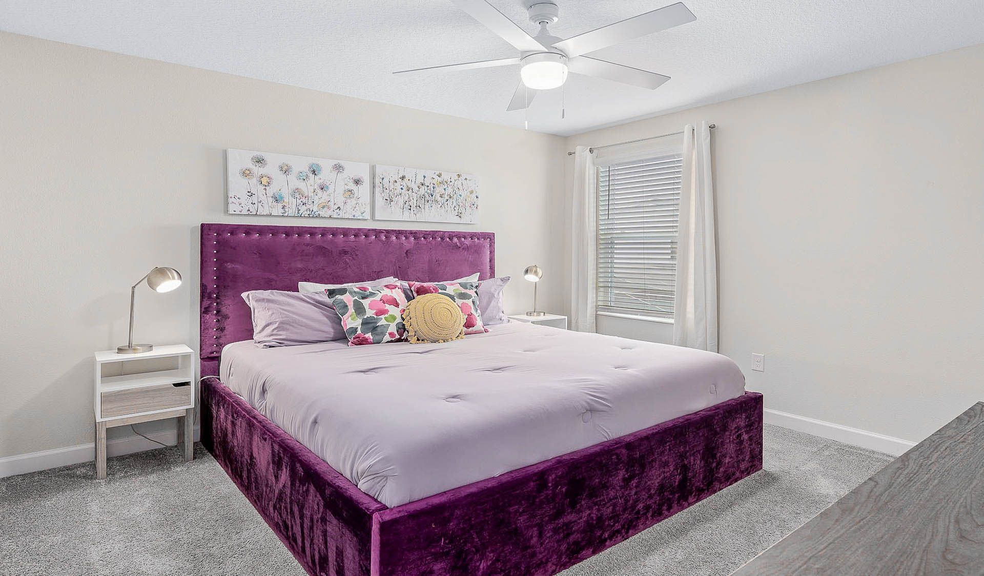 Cozy bedroom with a plush purple bed, floral accents, and a serene atmosphere!