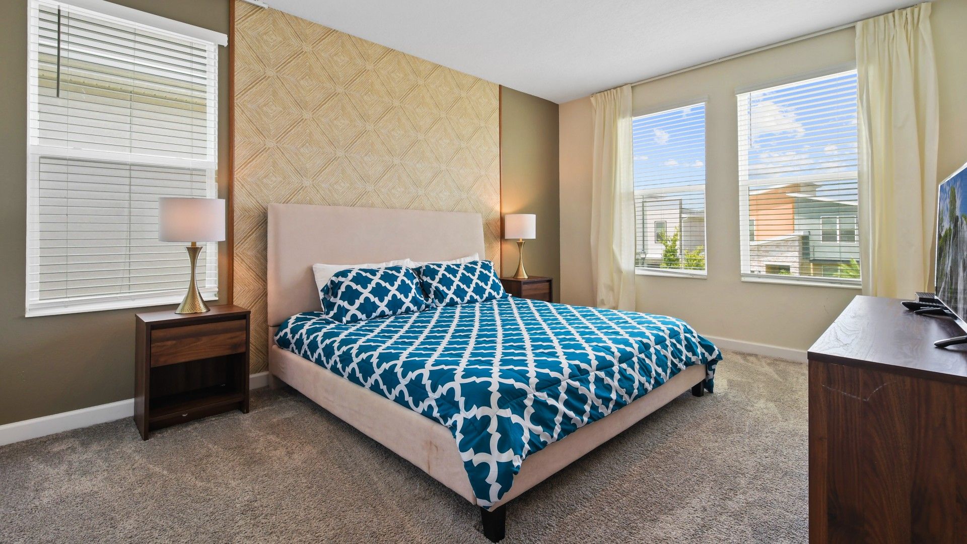 Spacious bedroom with a plush bed, stylish decor, and bright natural lighting