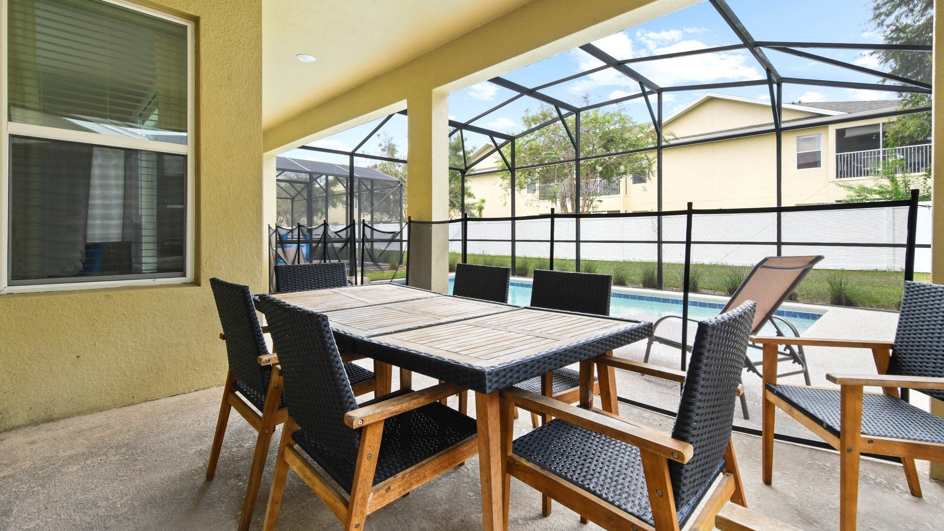 Relaxing covered patio with stylish outdoor dining, pool views, and cozy seating