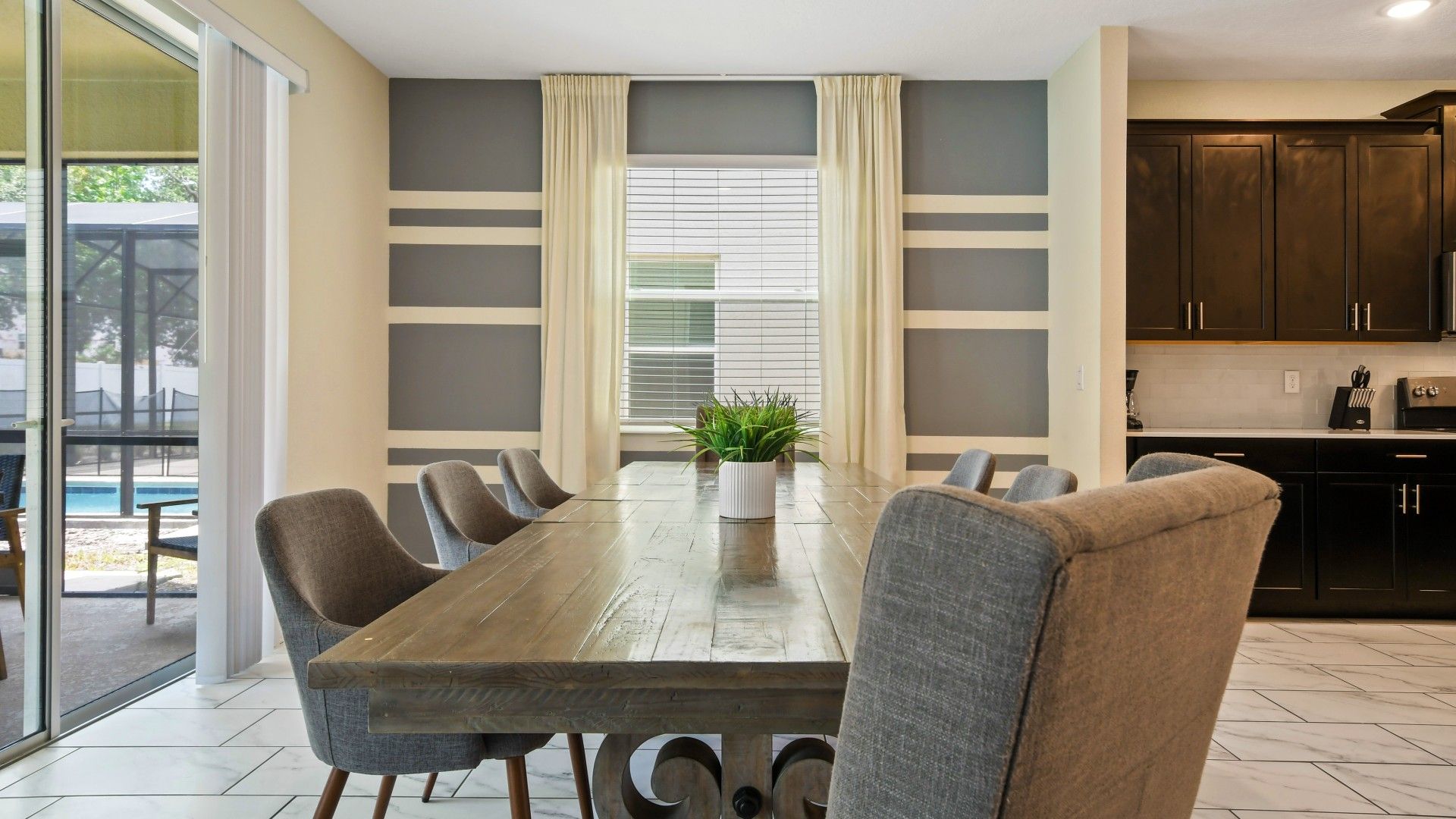 Elegant dining area with a rustic table, stylish seating, and poolside views