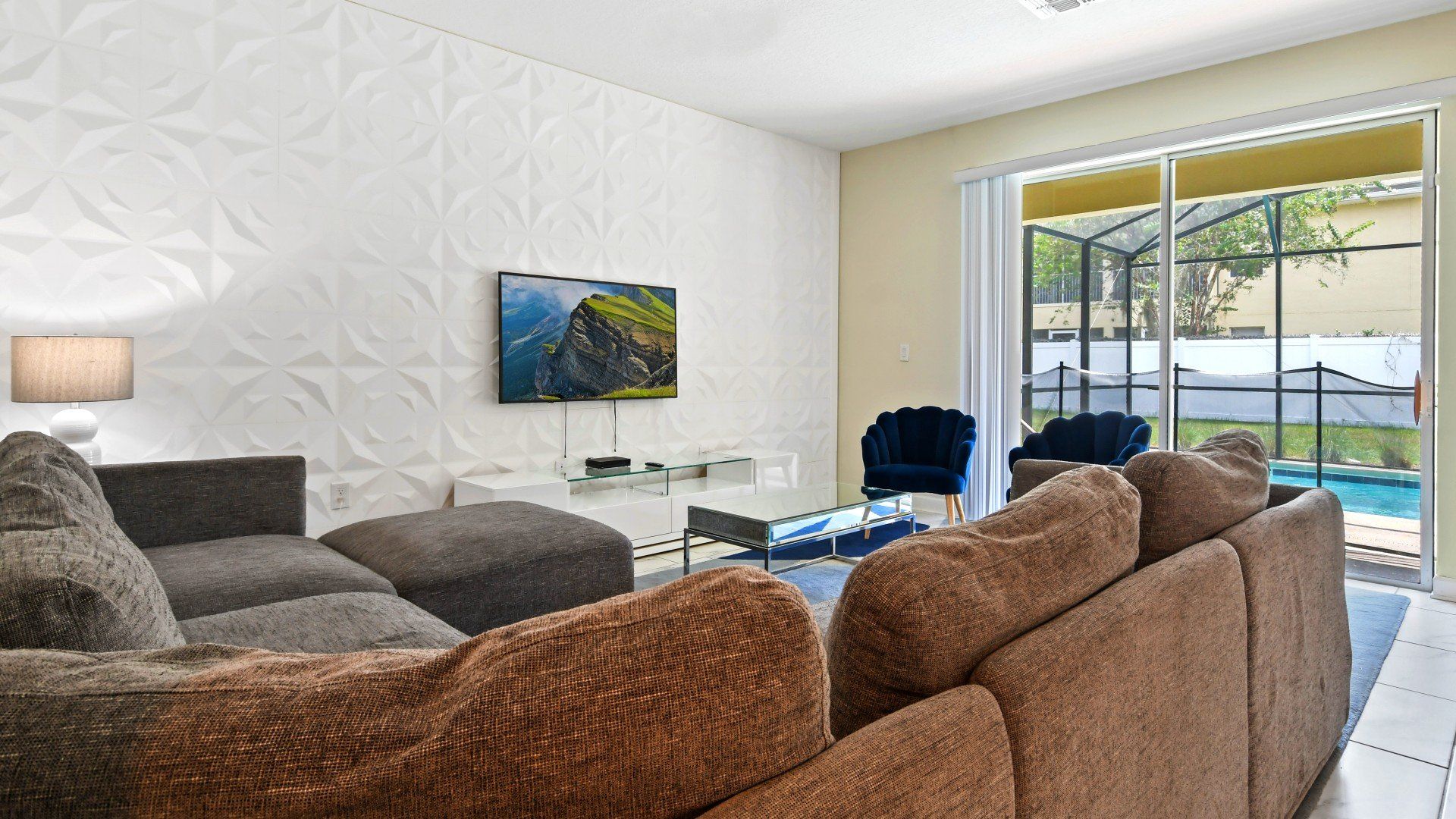 Stylish living space with cozy seating, pool views, and a modern entertainment setup