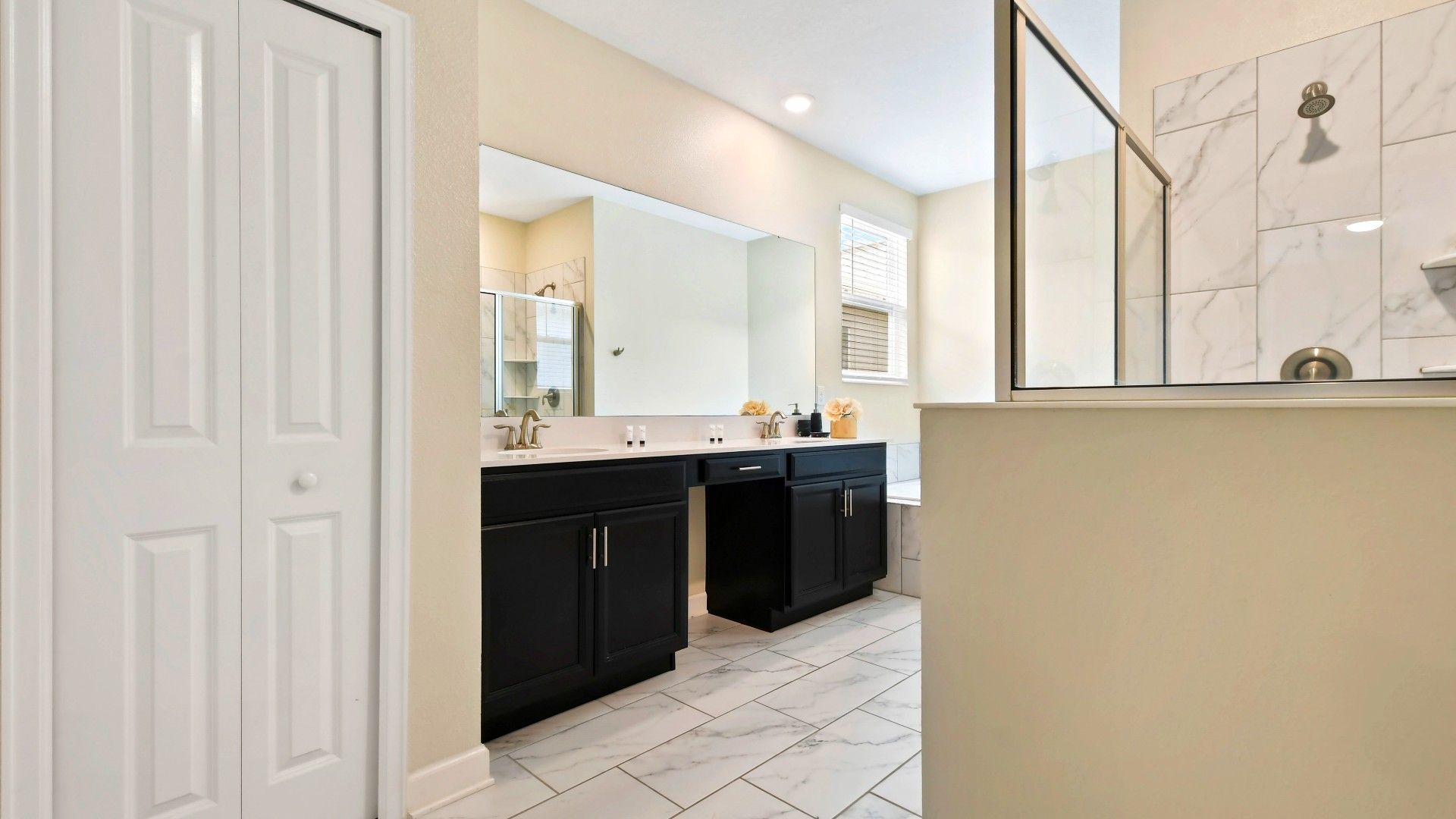 Spacious and elegant bathroom with a double vanity, marble finishes, and a glass shower