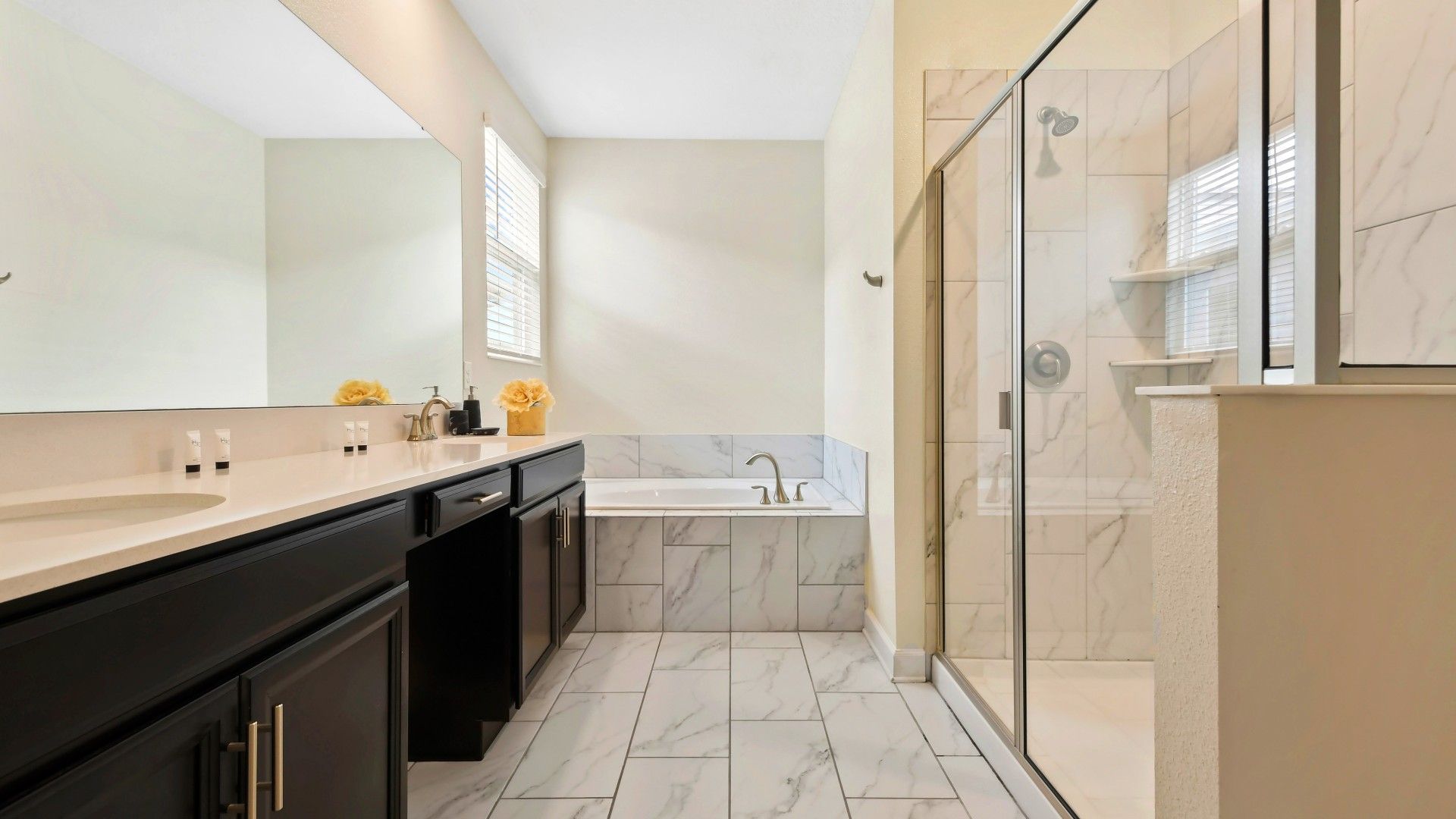 Luxurious bathroom with a double vanity, marble finishes, a soaking tub, and a glass shower