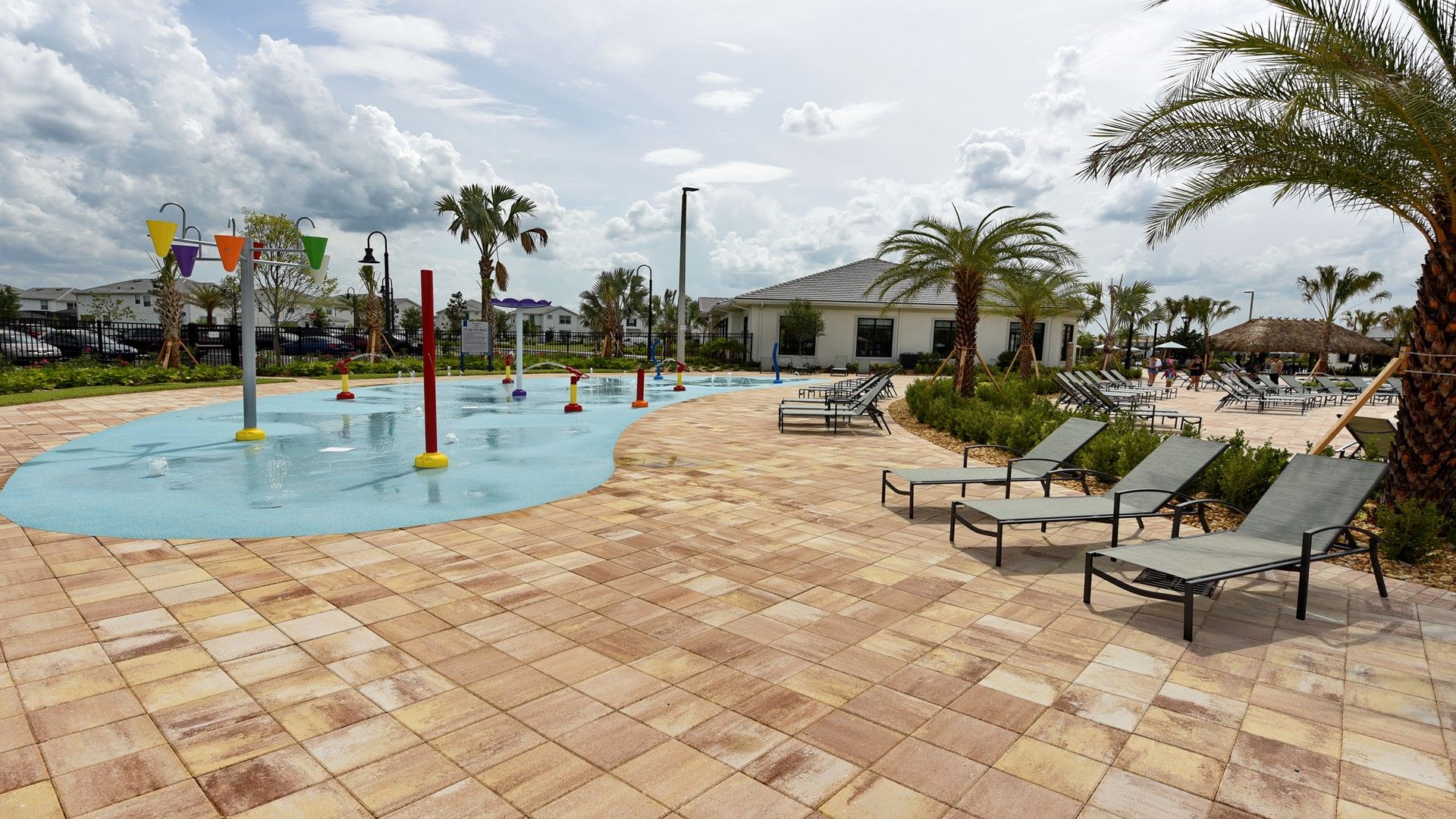 Family-friendly splash pad with loungers, palm trees, and sunny resort vibes.