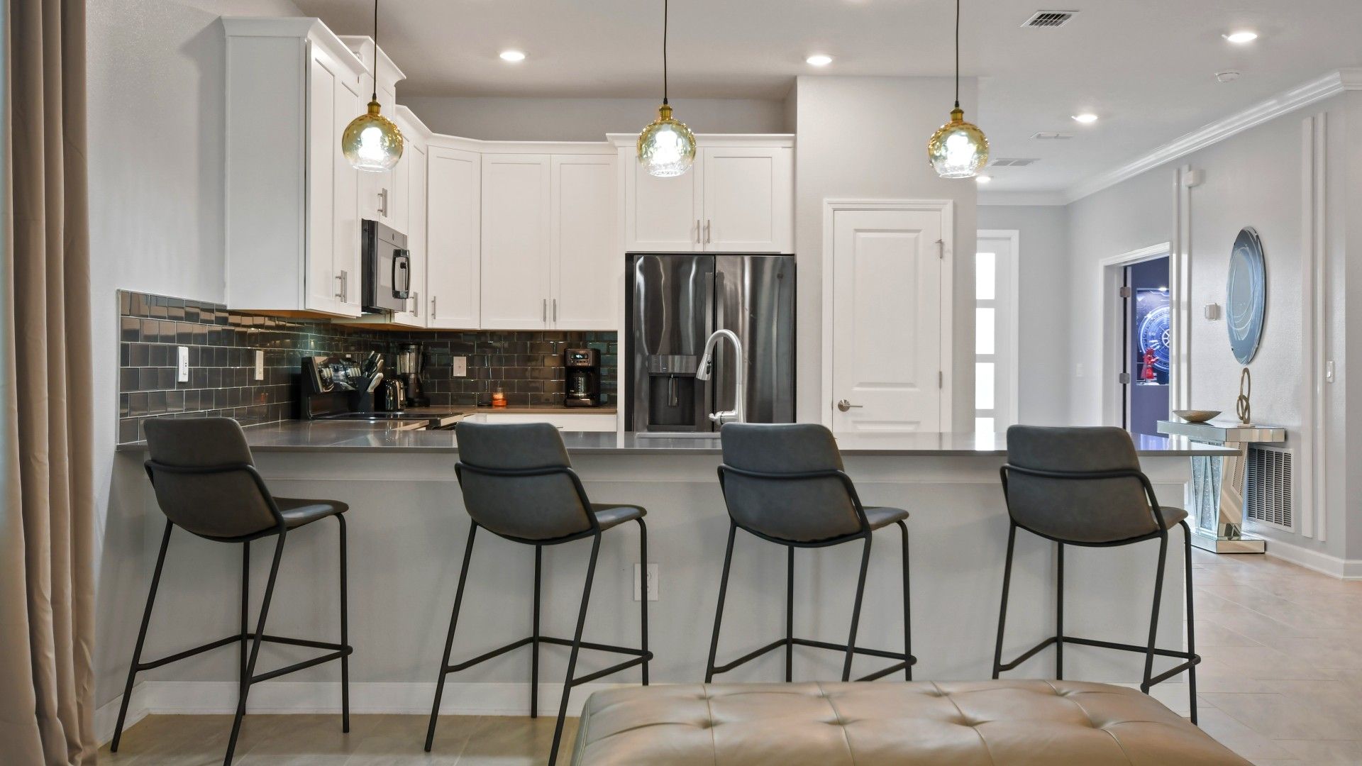 Modern kitchen with sleek black tile, stylish pendant lighting, and island seating.