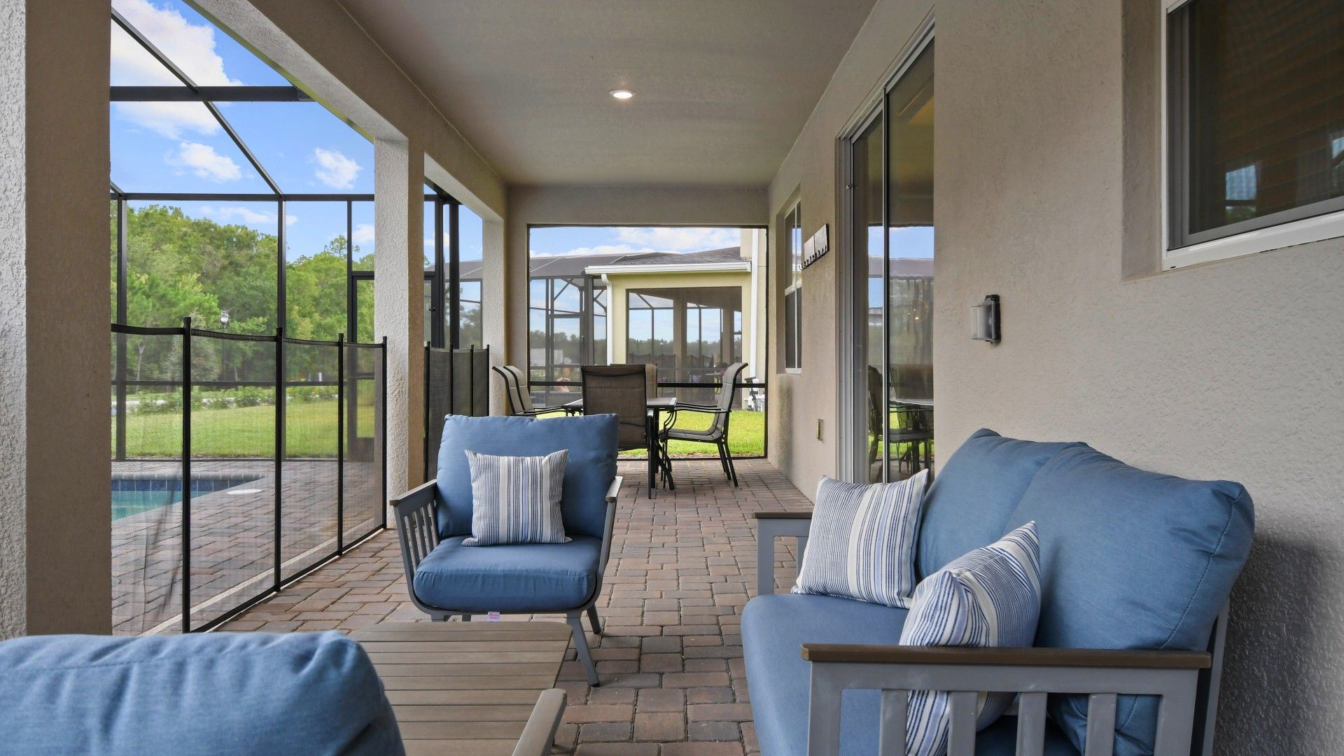 Relaxing screened-in patio with cozy seating, outdoor dining, and serene pool views.
