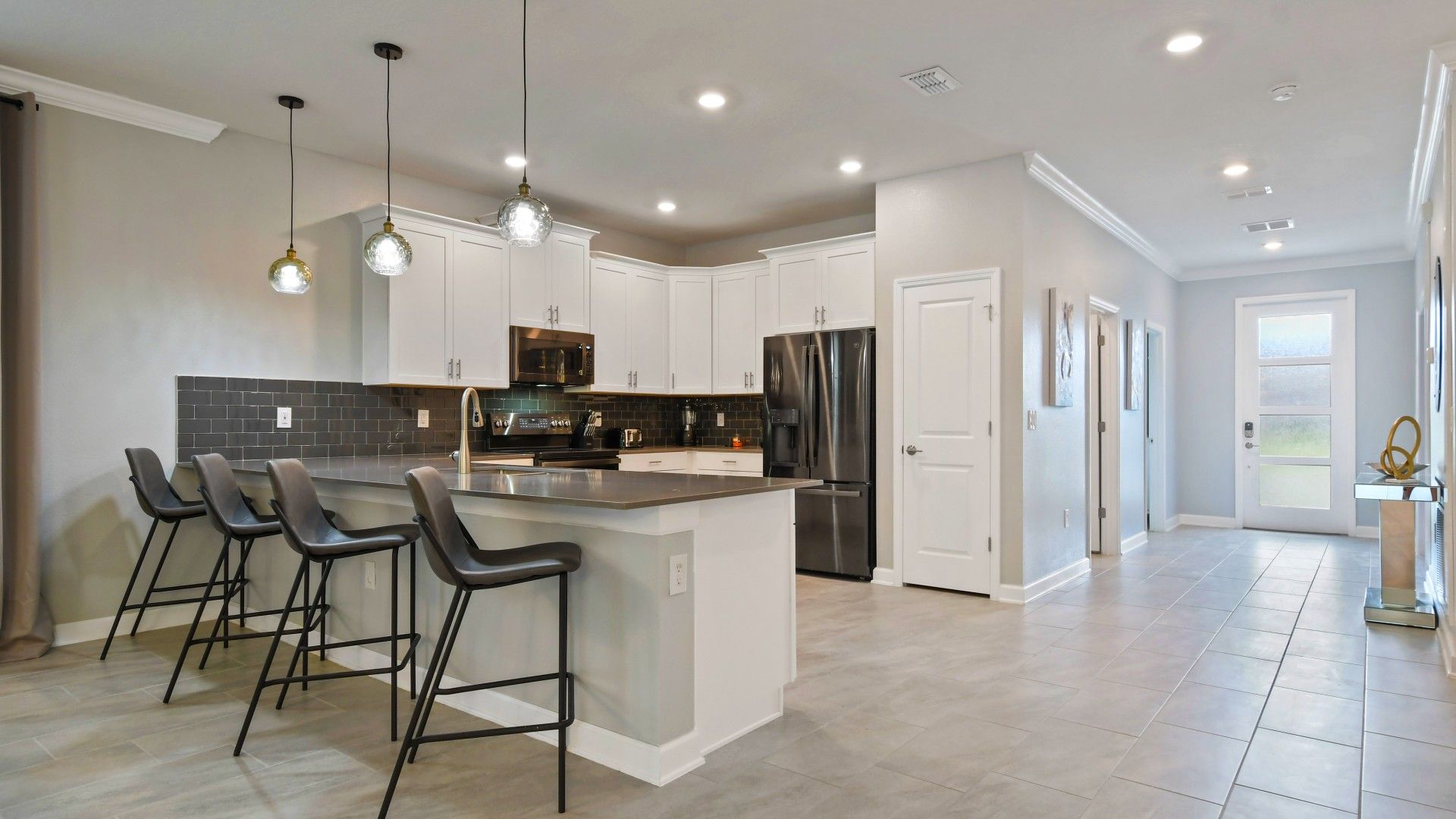 Sleek modern kitchen with black accents, stylish lighting, and spacious island seating.