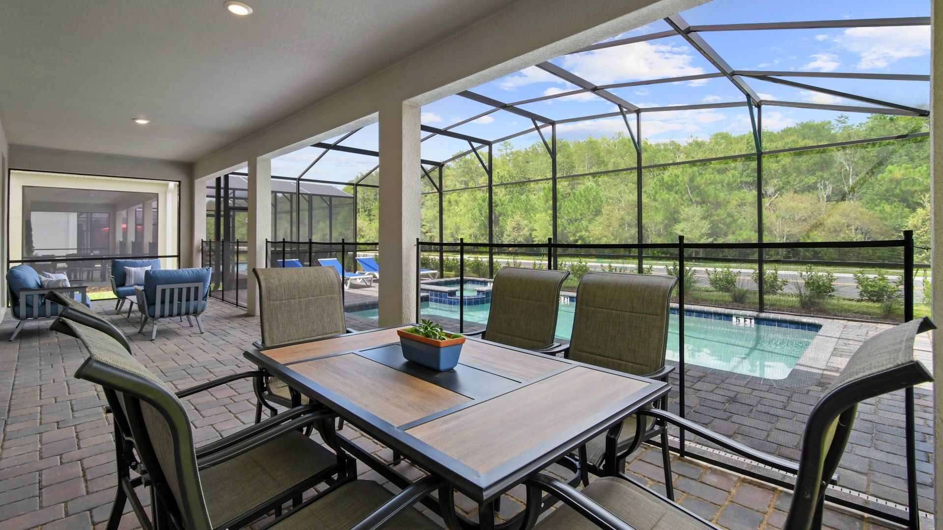 Spacious screened-in patio with outdoor dining, cozy seating, and a private pool view.