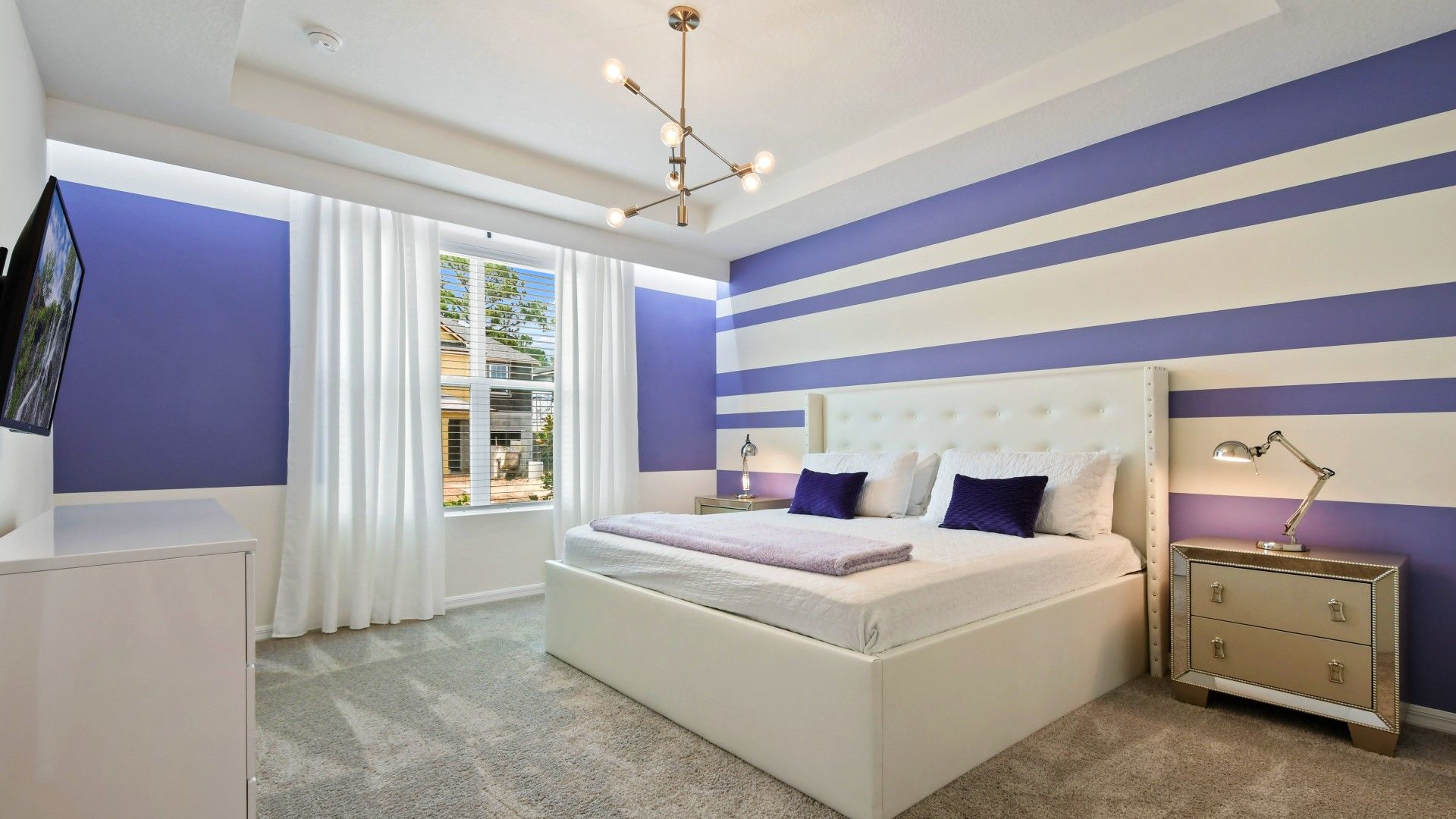 Stylish bedroom with modern decor, bold stripes, plush bedding, and natural light!