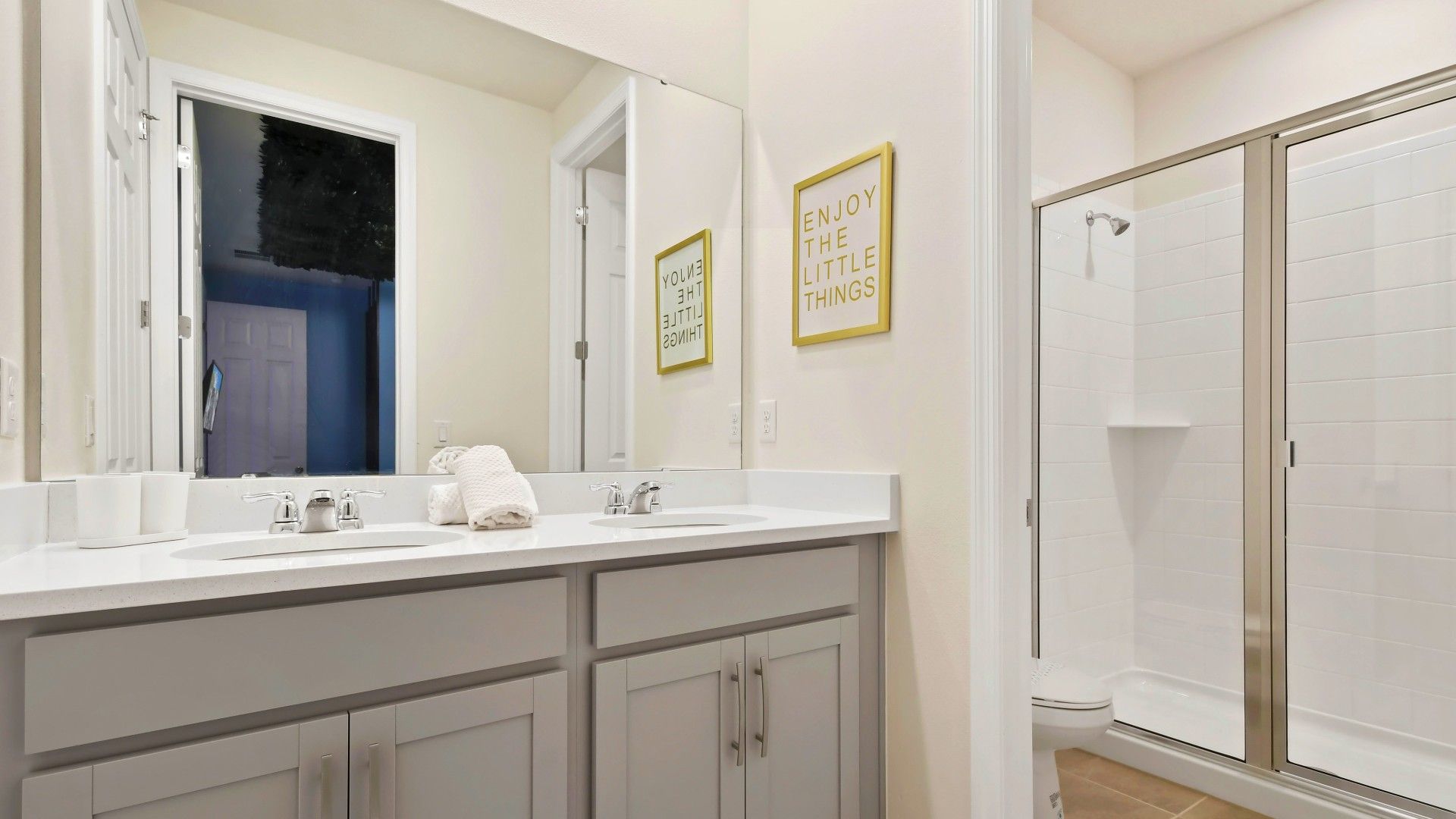 Bright, modern bathroom with dual sinks, walk-in shower, and cheerful decor!