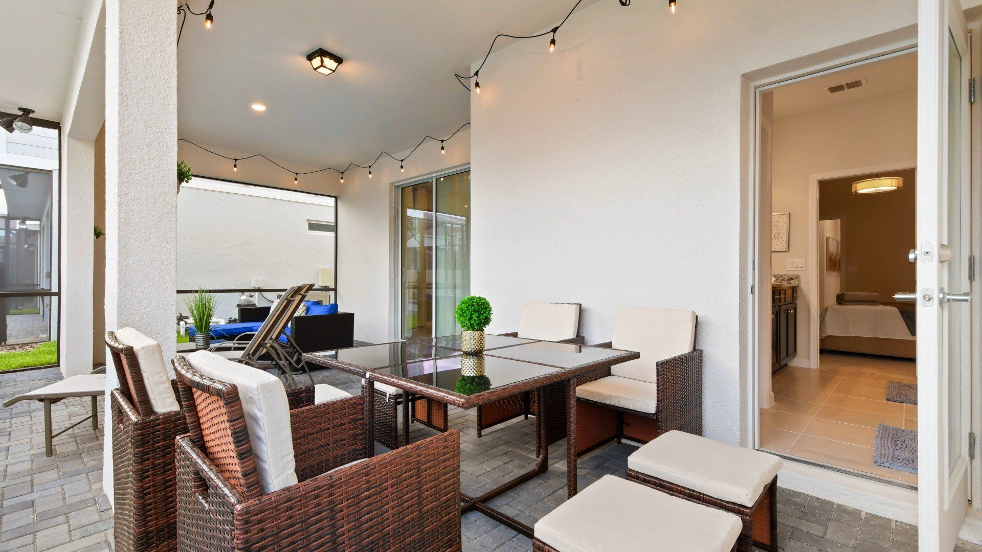 Covered patio with string lights, dining set, and easy indoor-outdoor flow to bedroom.