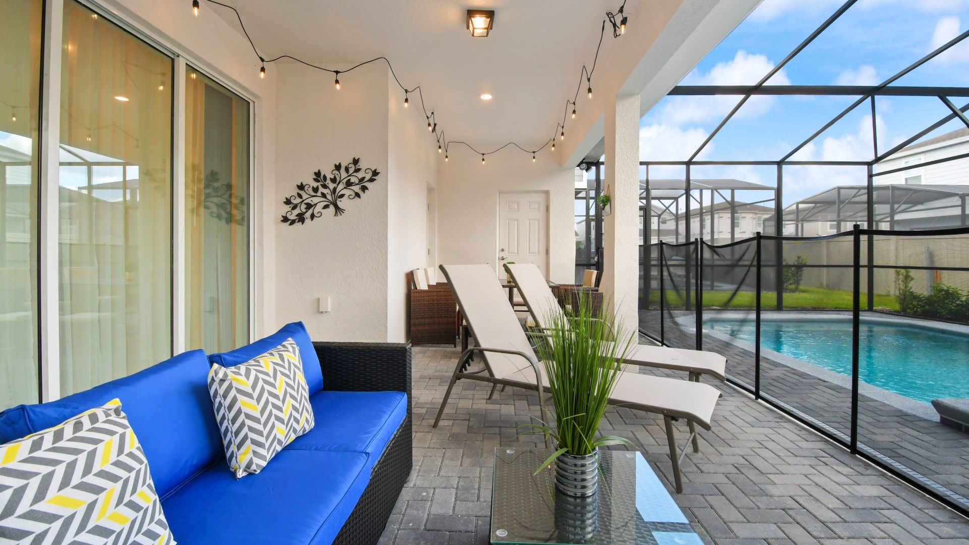 Chic poolside lounge with string lights, cushioned seating, and relaxing recliners.