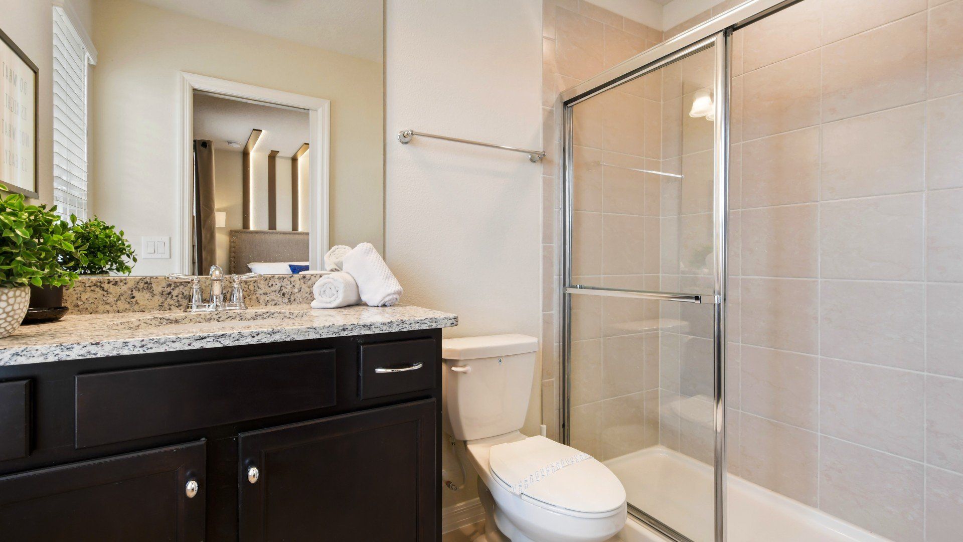 Modern bathroom with glass shower, granite countertop, and sleek dark cabinetry.