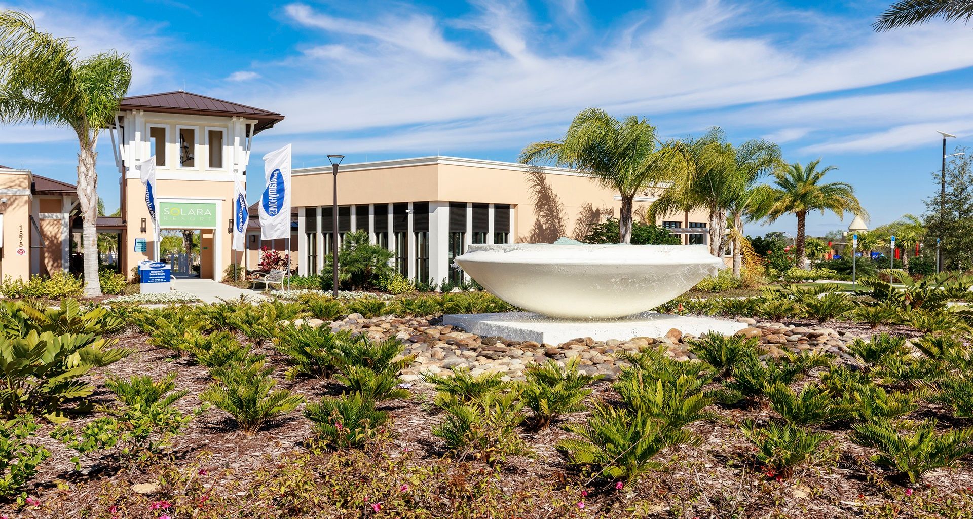 Stunning resort entrance with lush landscaping, fountain, and palms!