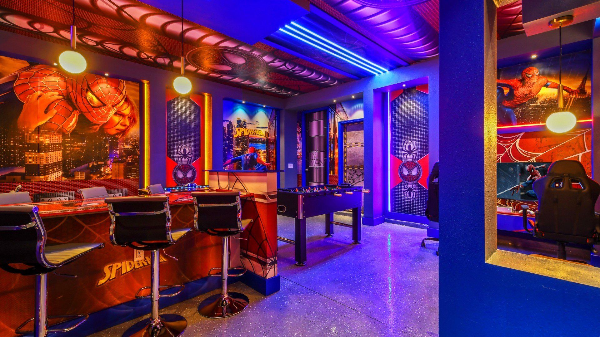 Colorful superhero-themed game room with arcade games, foosball, and bar seating.