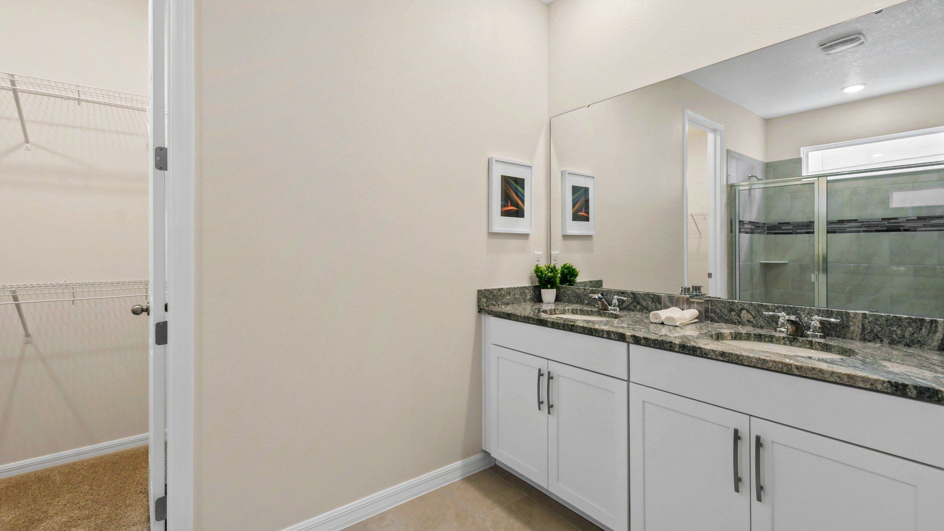 Spacious bathroom with dual sinks, granite countertops, and a walk-in closet.