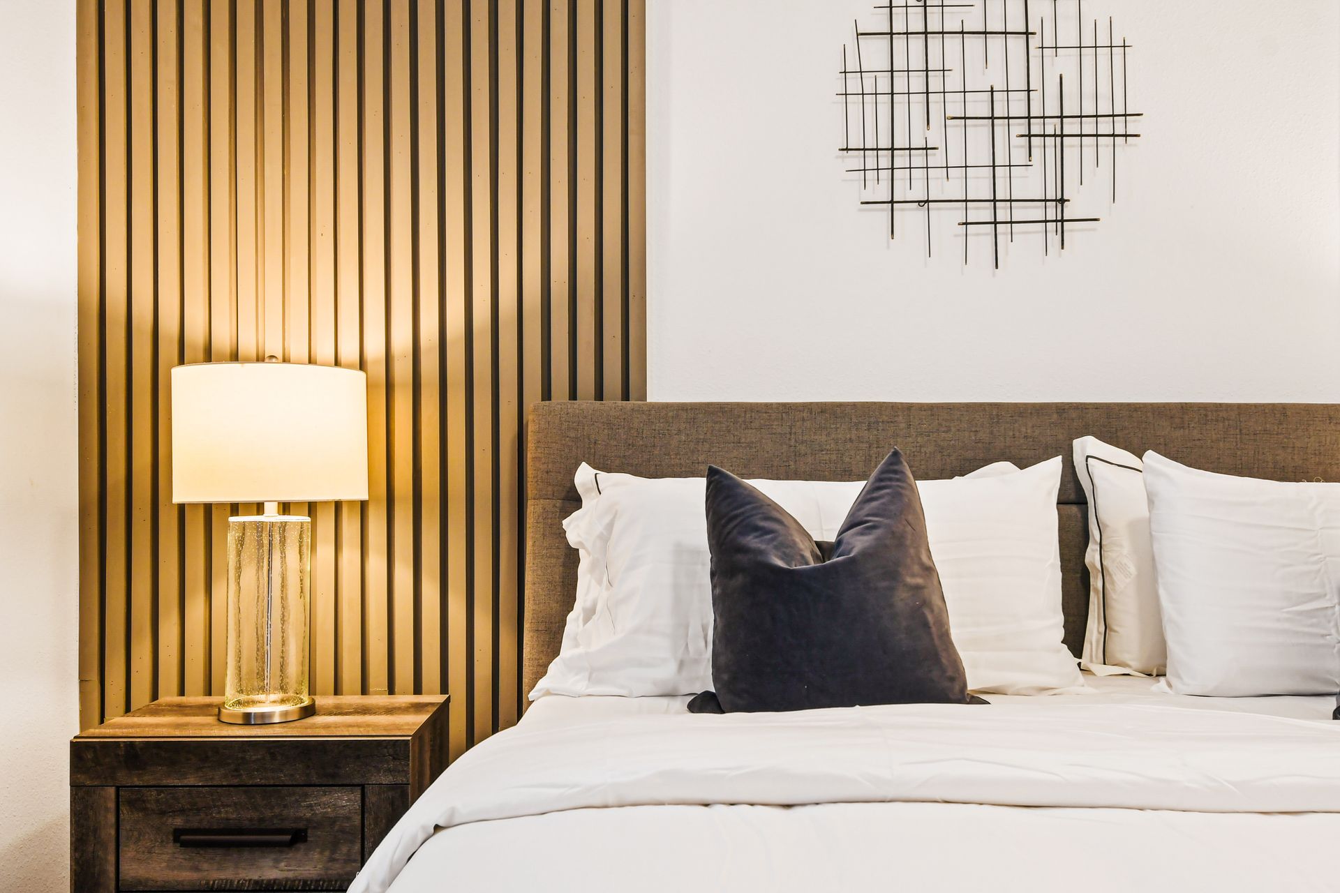 Modern bedroom with cozy textures, warm lighting, and stylish accent wall