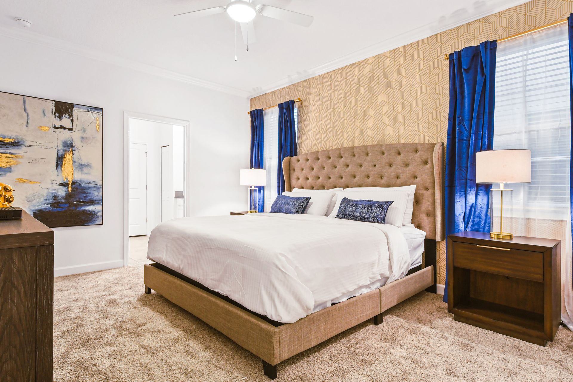 Luxurious bedroom with king bed, bold blue drapes, and elegant gold accents