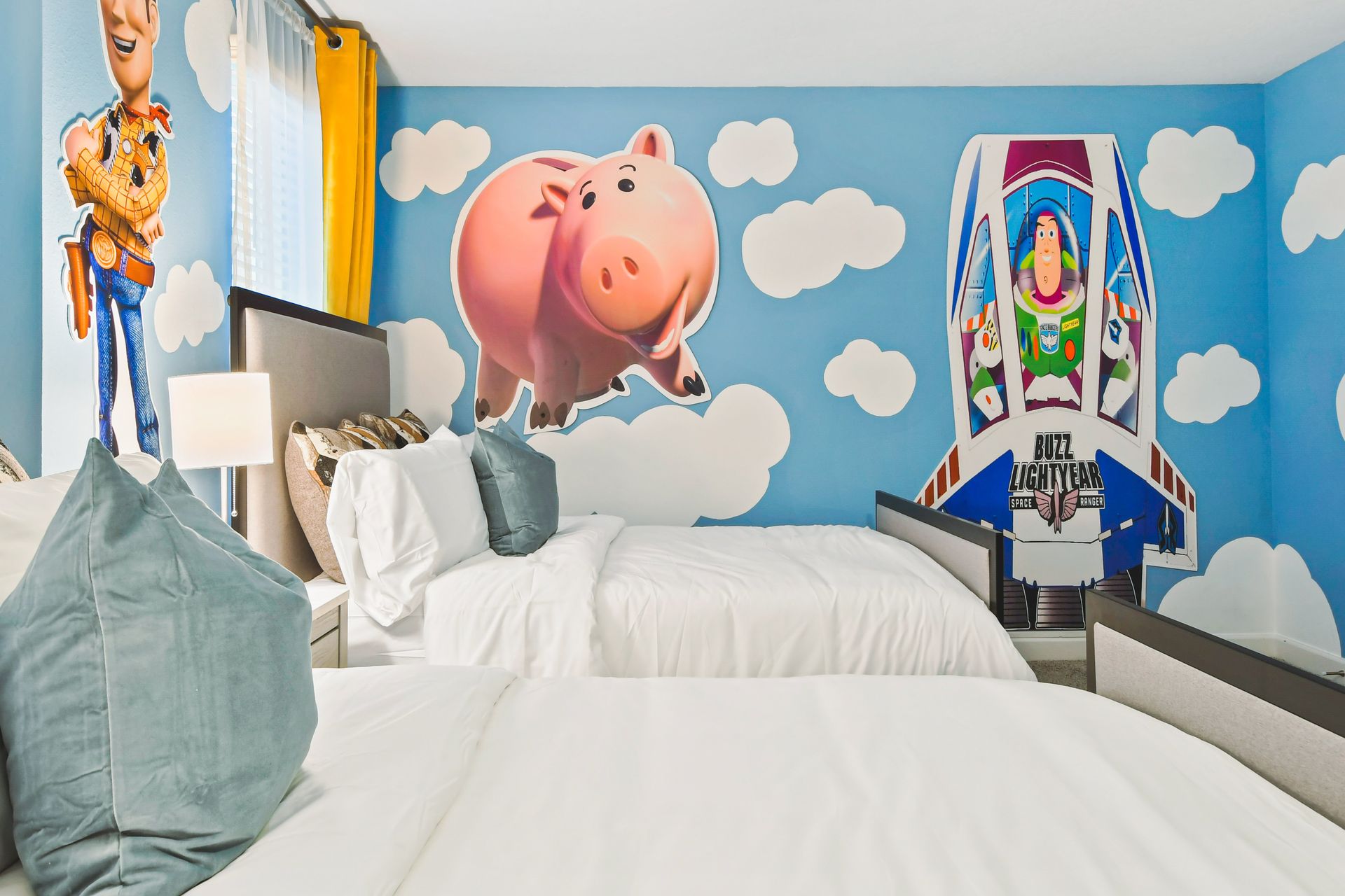 Toy Story-themed bedroom with three beds, playful wall art, and bright decor