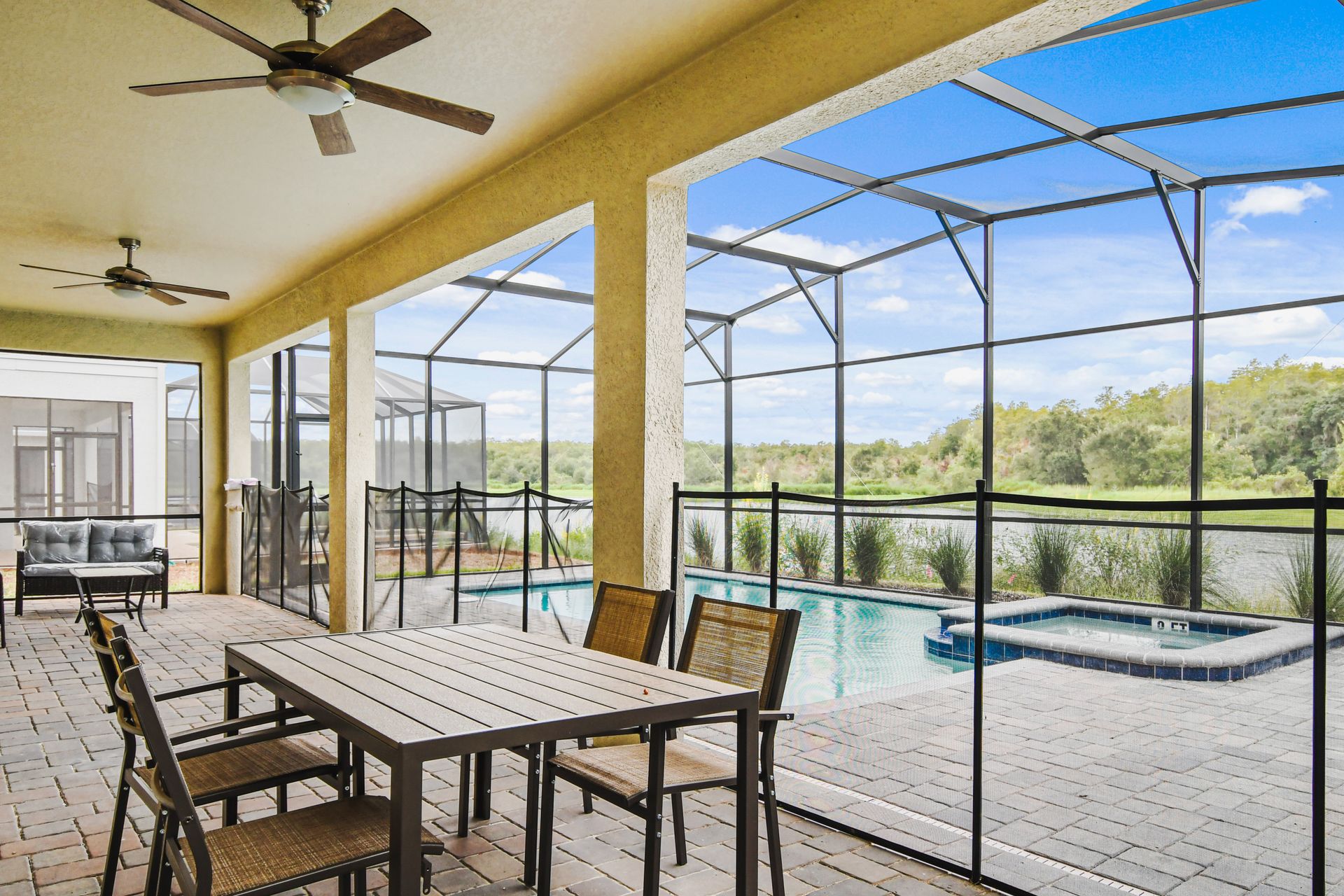 Spacious screened patio with dining, lounge seating, and poolside lake views