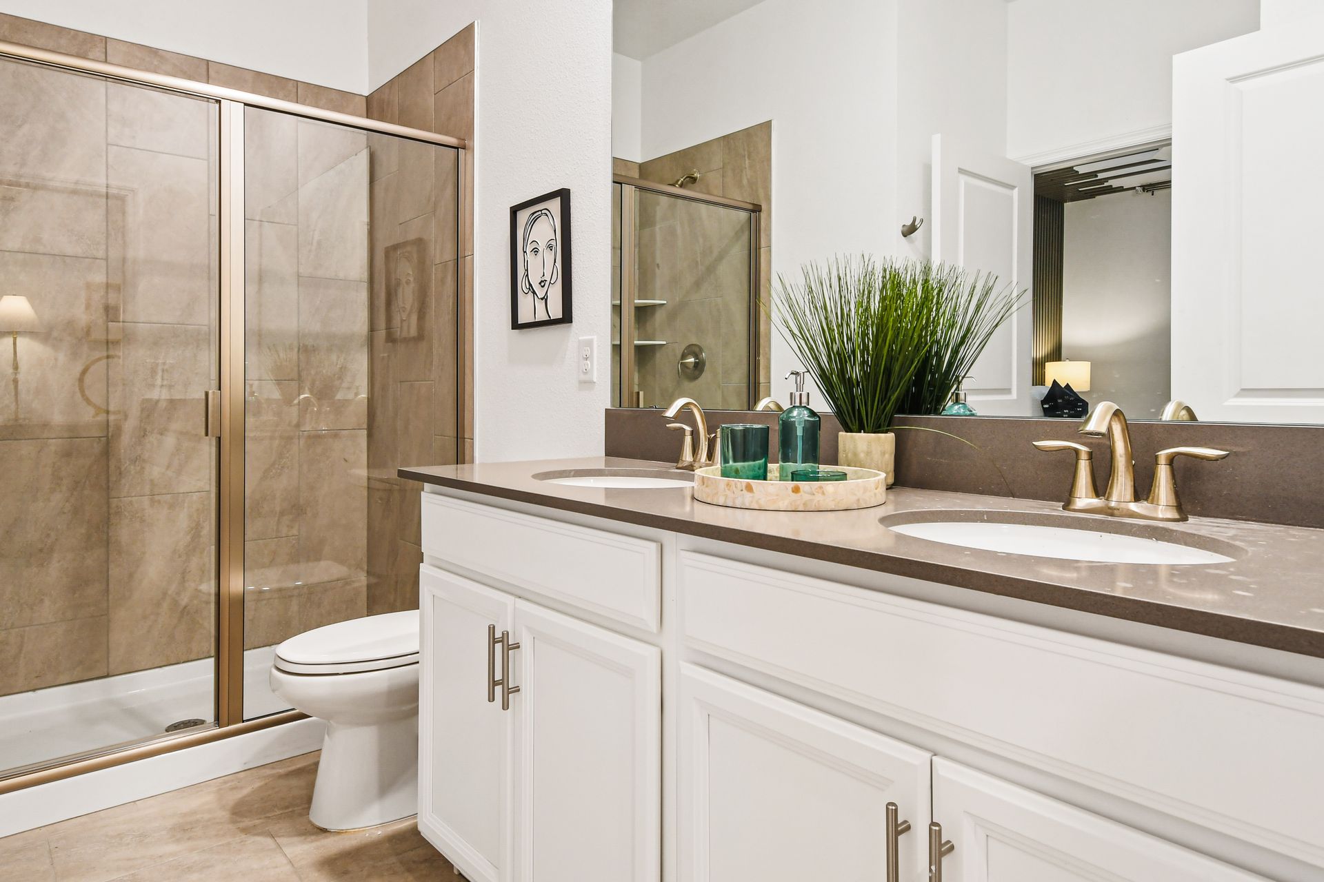 Elegant bathroom with double vanity, walk-in shower, and modern gold fixtures