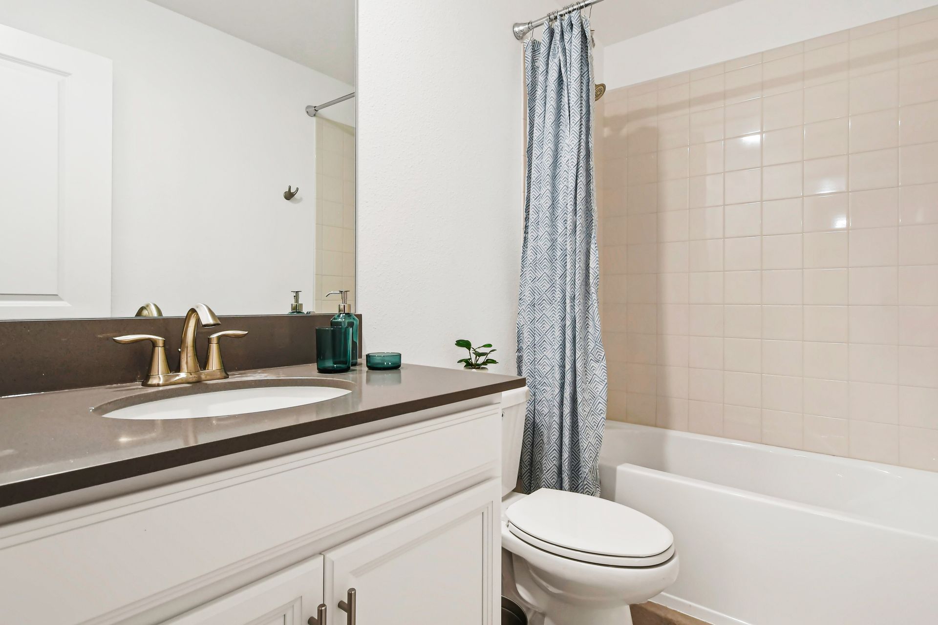 Bright and modern bathroom with tub, sleek vanity, and stylish gold fixtures