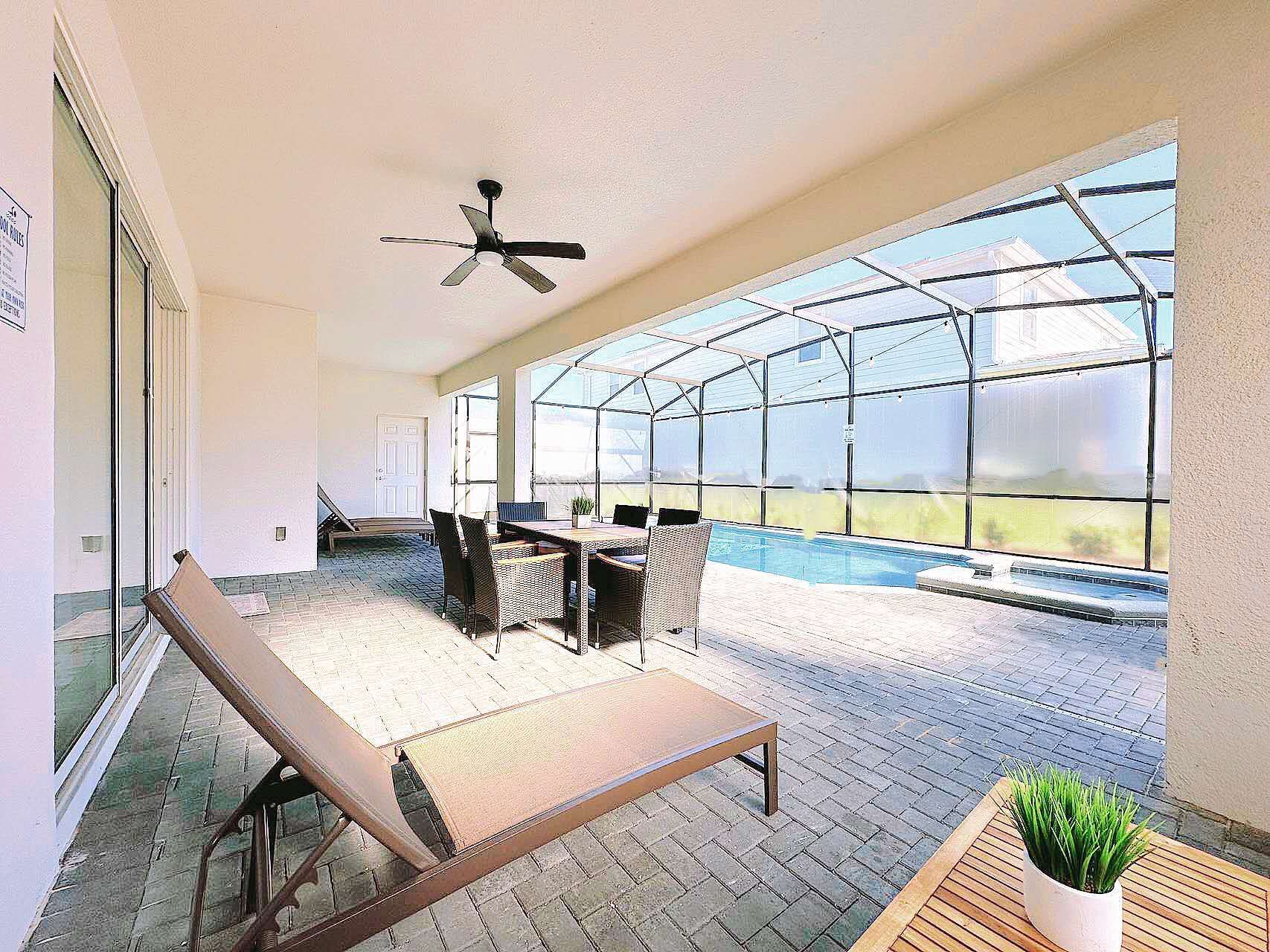 Spacious covered patio with pool views, dining area, and lounge chairs for relaxation.